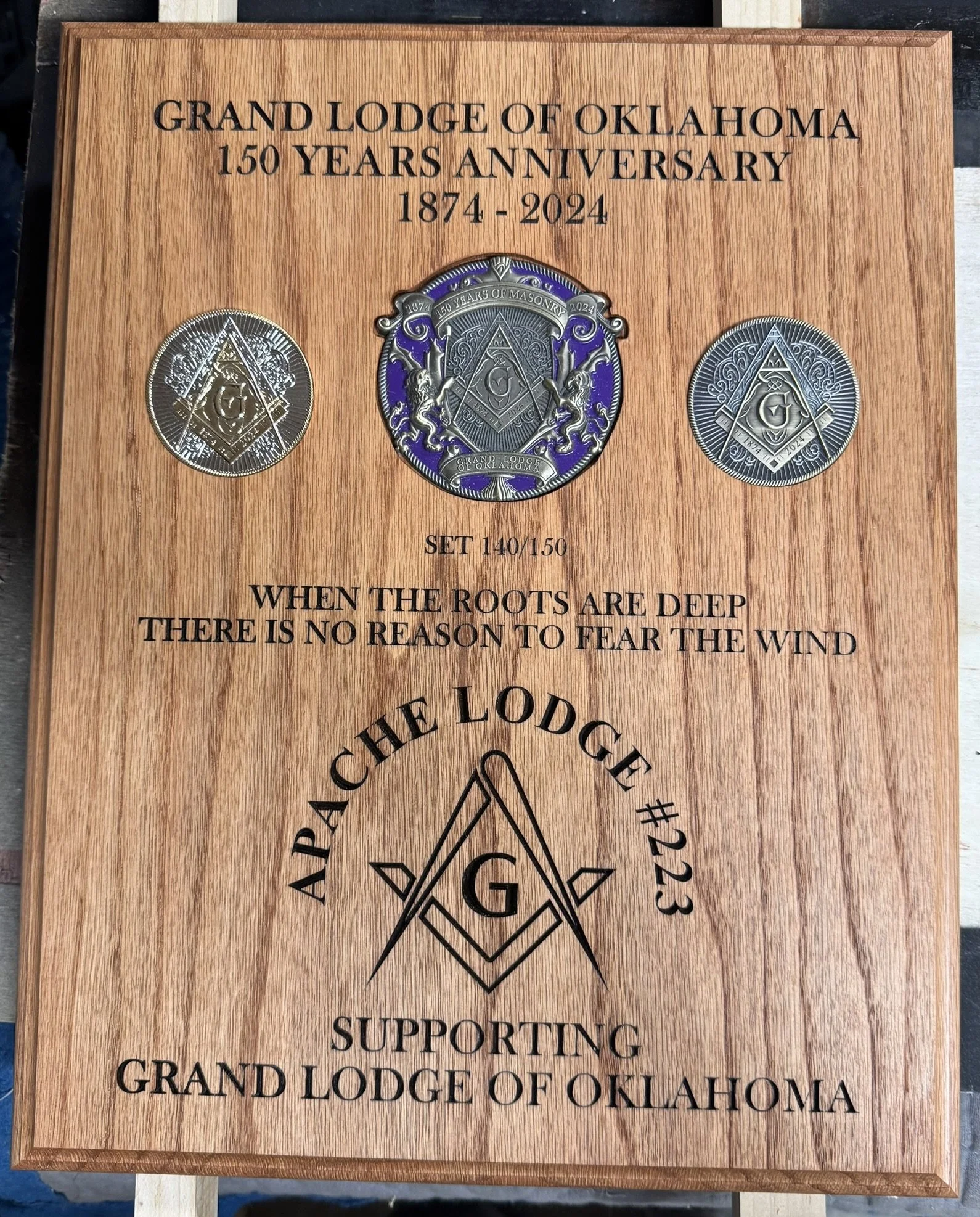 A wooden plaque commemorating the 150th anniversary of the Grand Lodge of Oklahoma, 1874-2024, with a Masonic emblem and engravings.