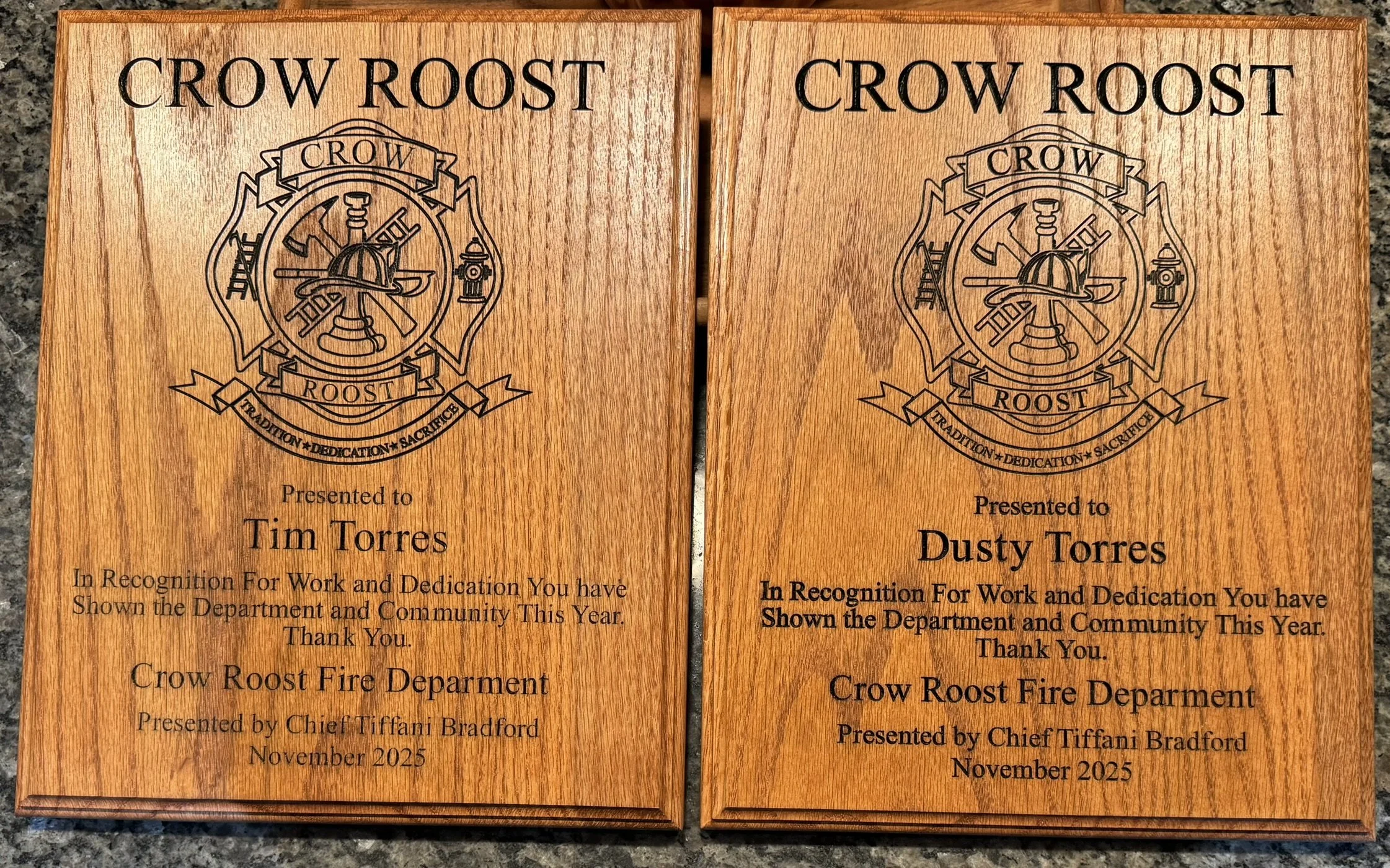 Two wooden plaques with the words "CROW ROOST" and a firefighter emblem engraved on them. The plaques are presented to Tim Torres and Dusty Torres in recognition of work and dedication, from Crow Roost Fire Department, by Chief Tiffani Bradford, Nove