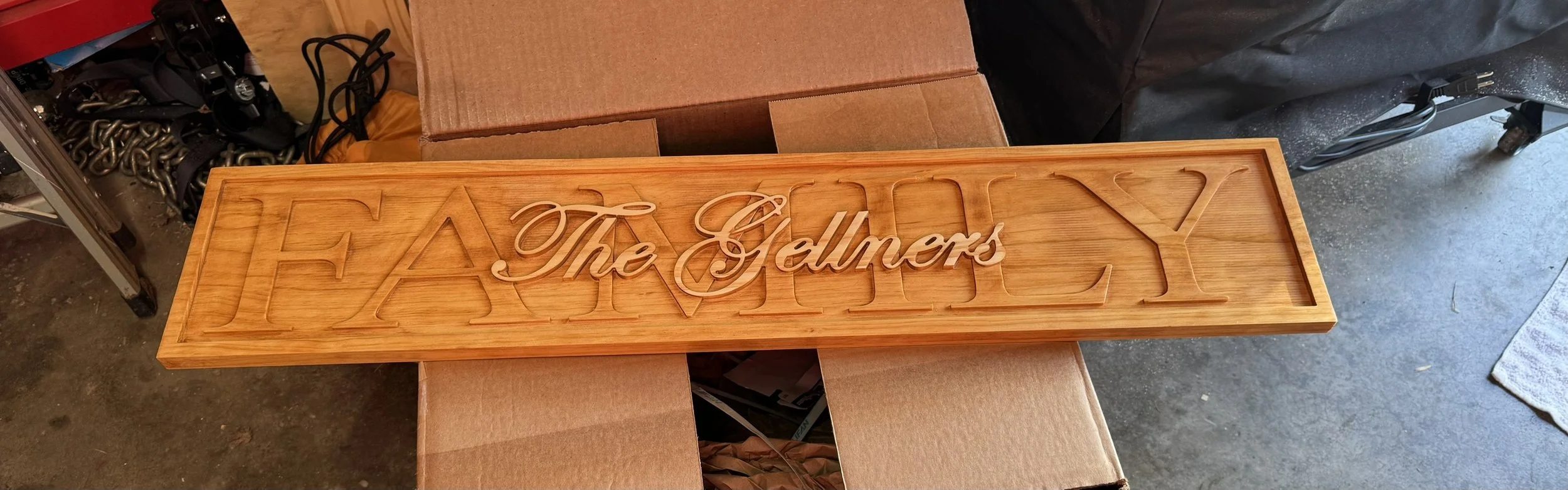 Wooden sign with carved lettering for The Gallows, laid on cardboard boxes