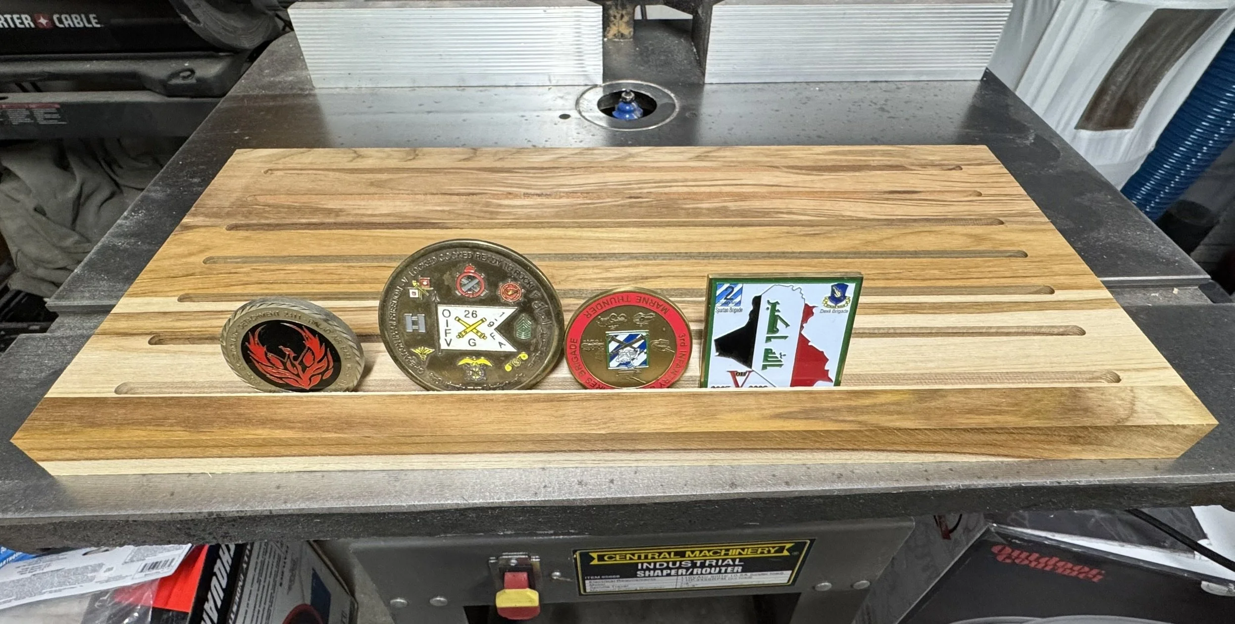 Wooden challenge coin display with routed grooves holding four military challenge coins. Crafted by Wichita Mountain Woodworks in Lawton, Oklahoma.