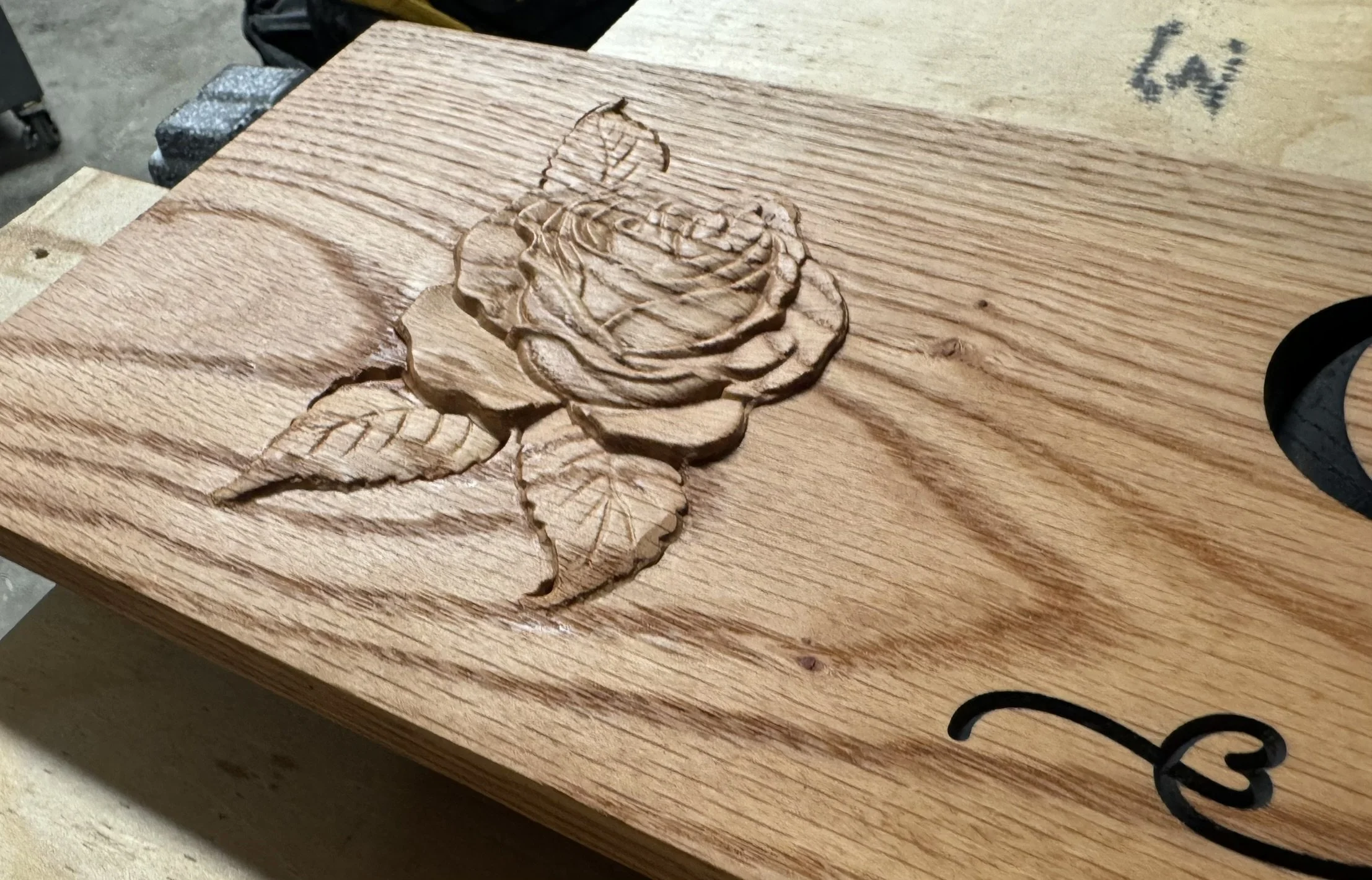 A piece of wood with a carved rose design on its surface.