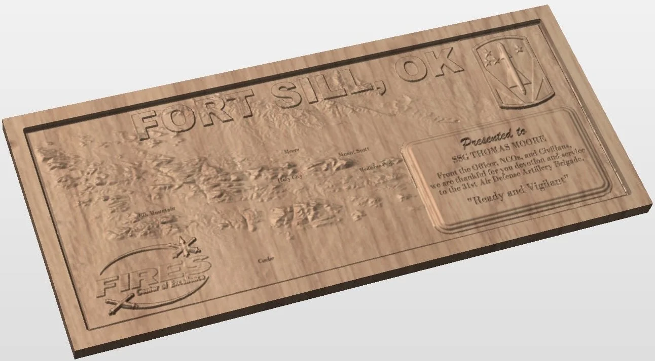 Wooden plaque with embossed map of Fort Sill, Oklahoma, featuring the fort's crest and a section with a message from the Air Defense Artillery Brigade about their role and readiness.