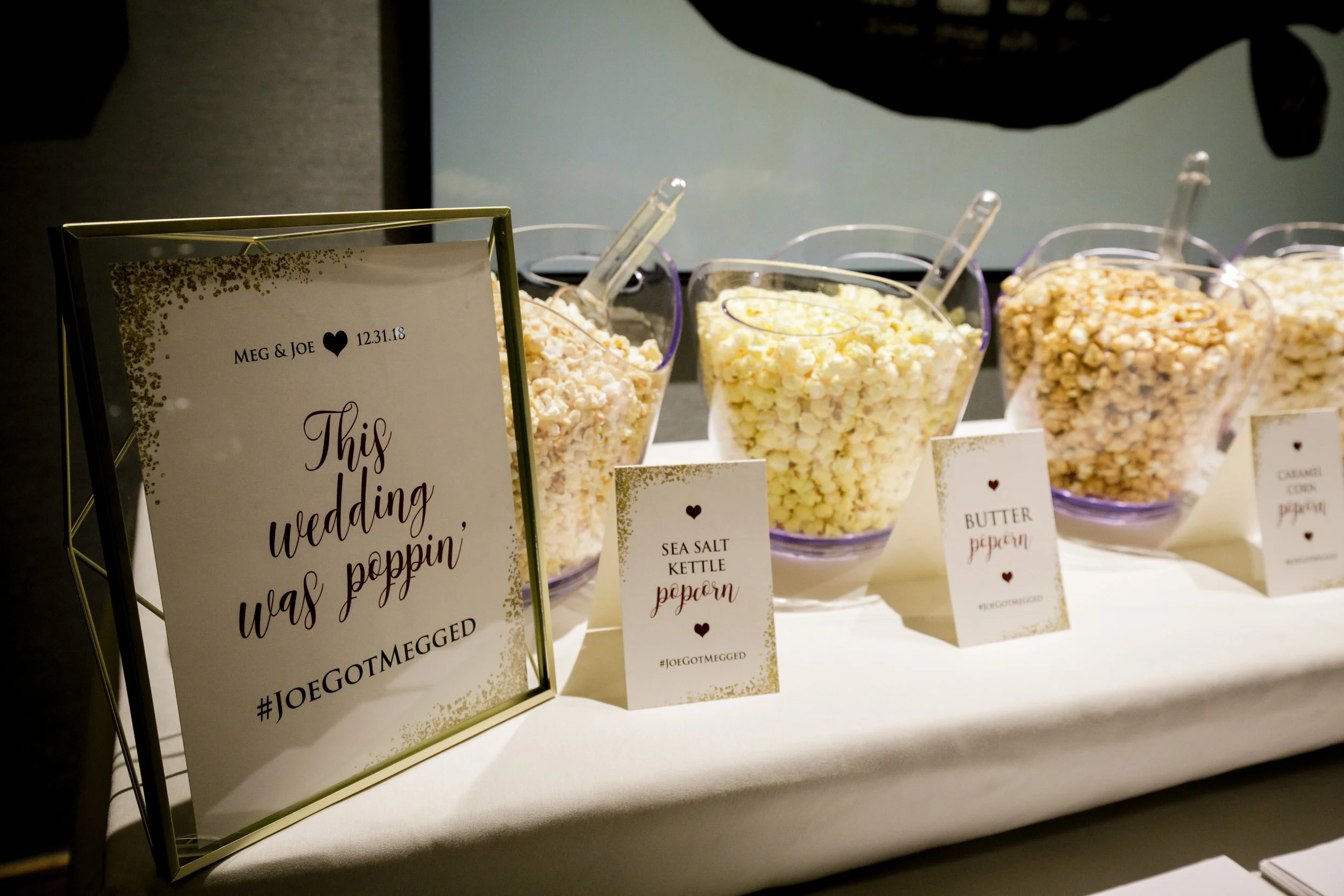 Display of popcorn flavors, including sea salt kettle and caramel, with a wedding sign in the foreground