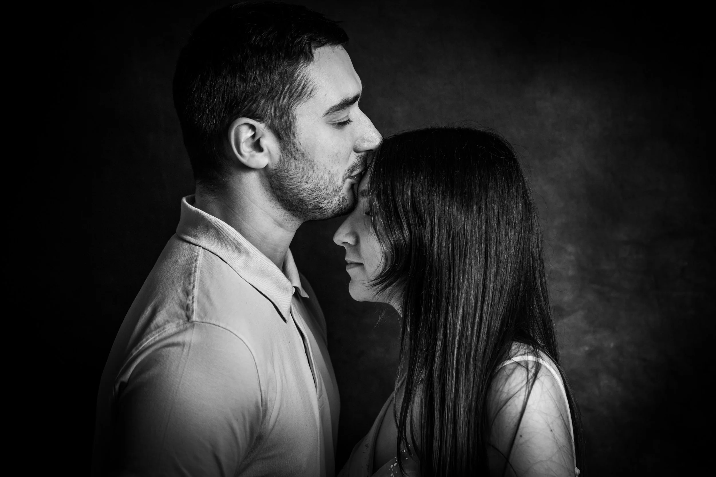 Un homme et une femme en gros plan, face à face, avec le front contre le front, dans une pose intime, en noir et blanc.