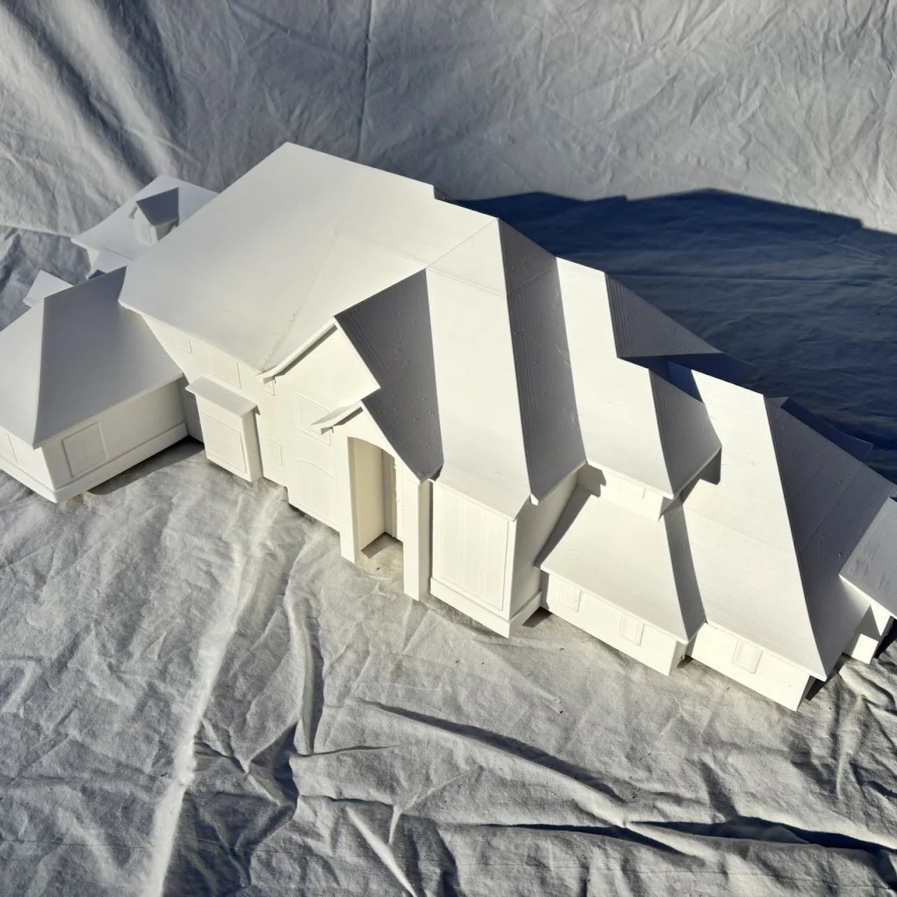 A white architectural model of a house showing multiple roof sections and a garage.