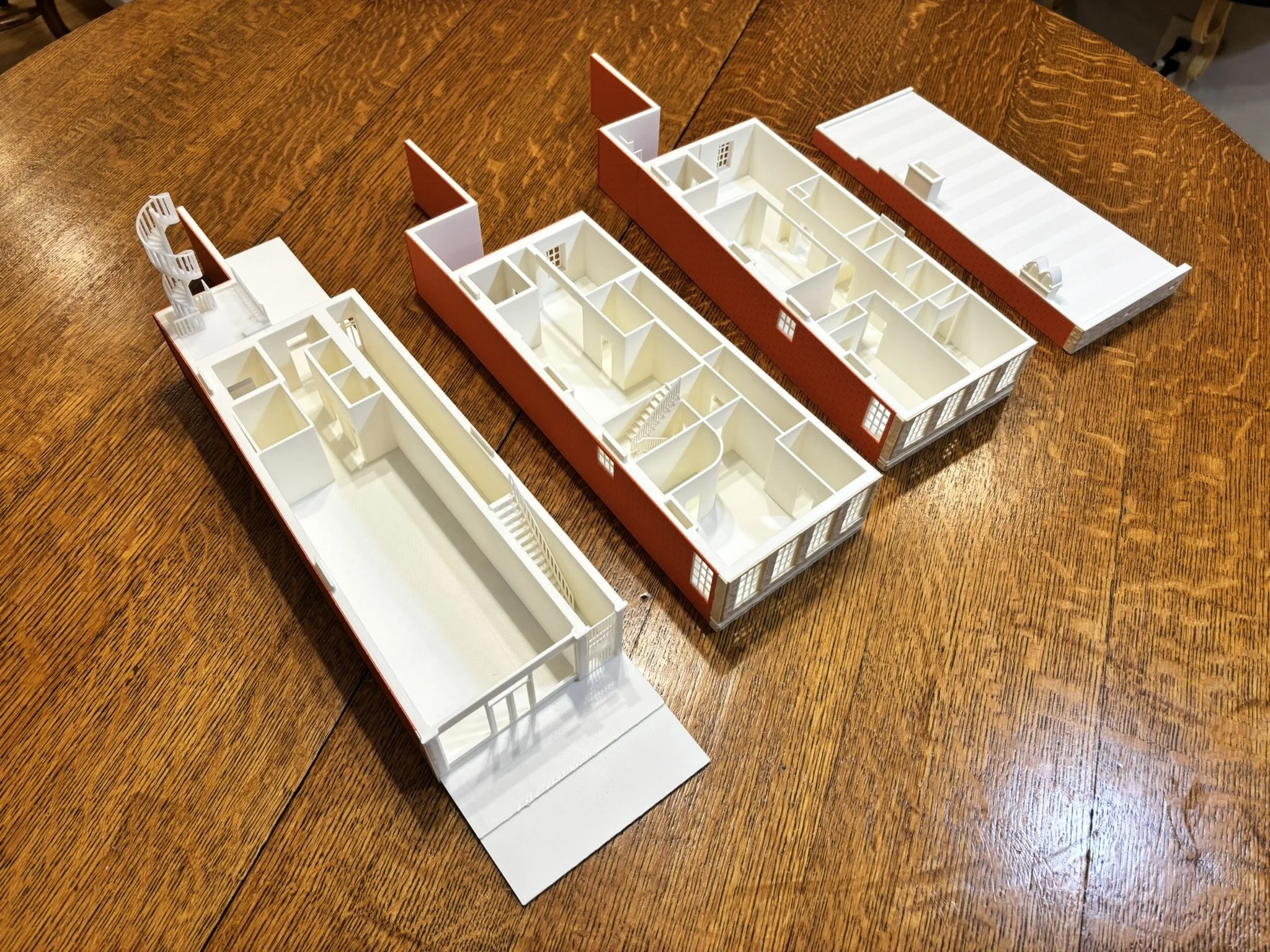 A white architectural model of a building with red exterior walls.