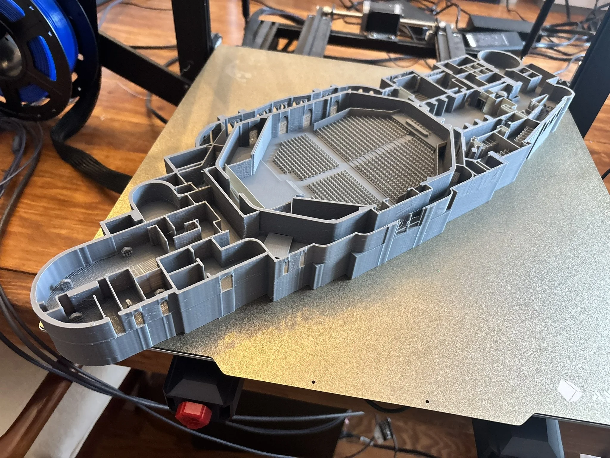A detailed gray 3D printed model of a theater with various rooms and structures visible inside making up the interior design of the model.