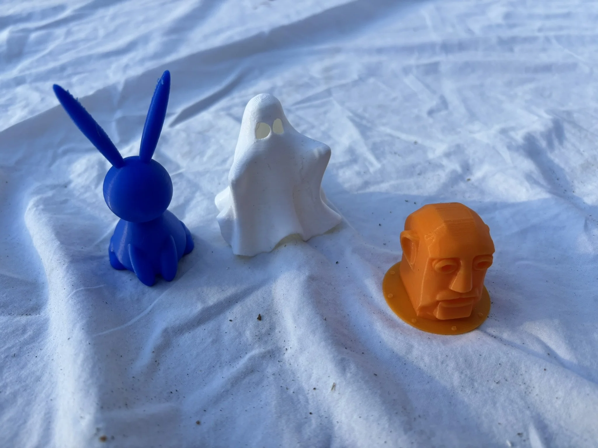 Colorful plastic toy animals on snow, including a blue rabbit, a white dolphin, and an orange bear.