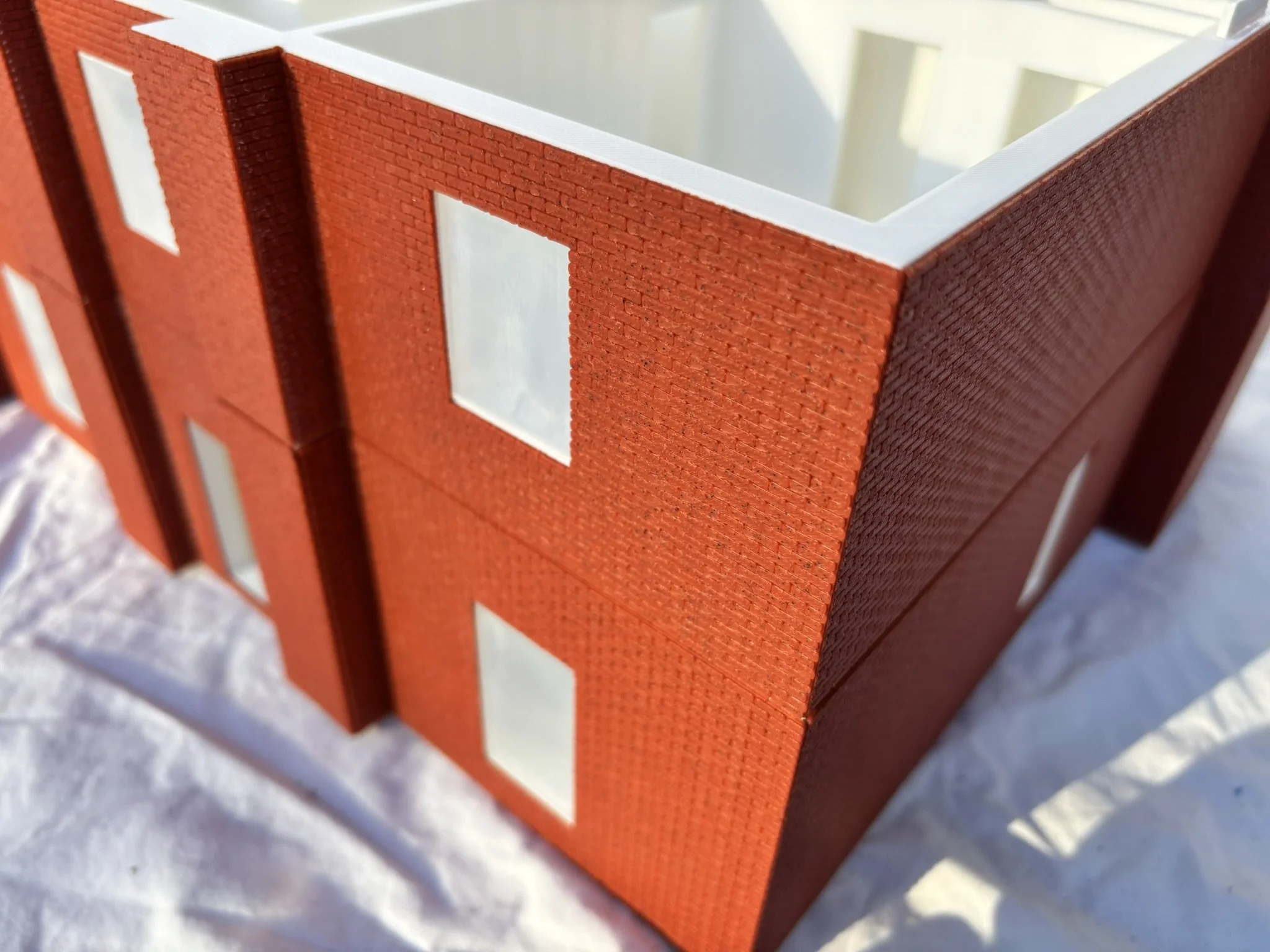Close-up of a miniature red brick building model with white window trim.