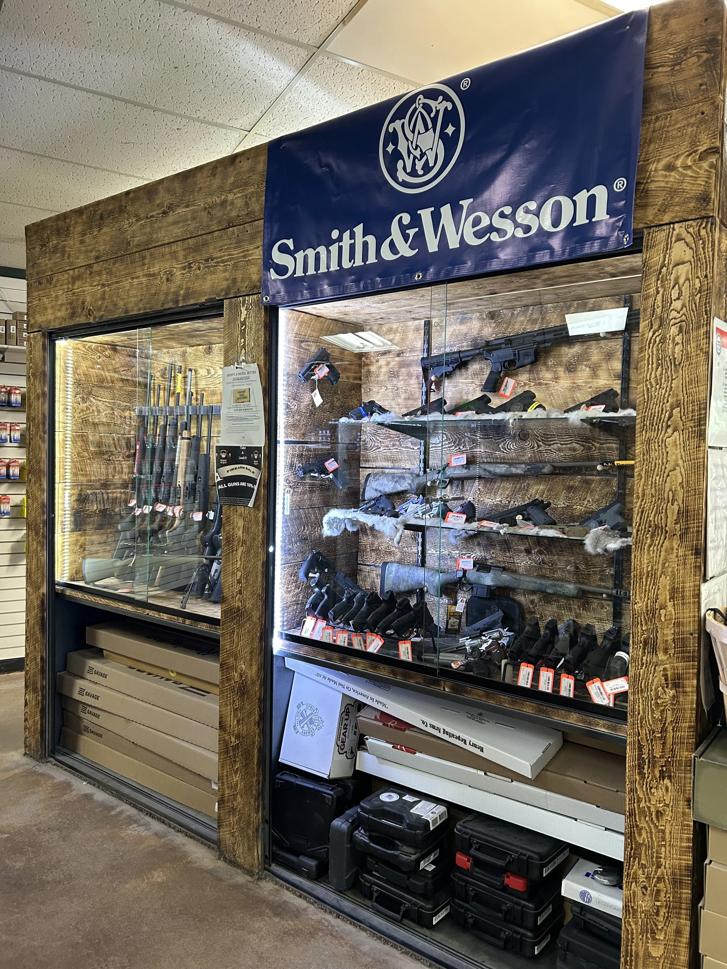 Display of firearms and firearm accessories in a glass case at Smith & Wesson store.