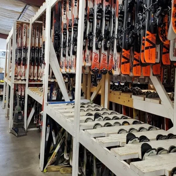 Ski racks with skis and snowboards organized on wooden shelves in a sporting goods store.