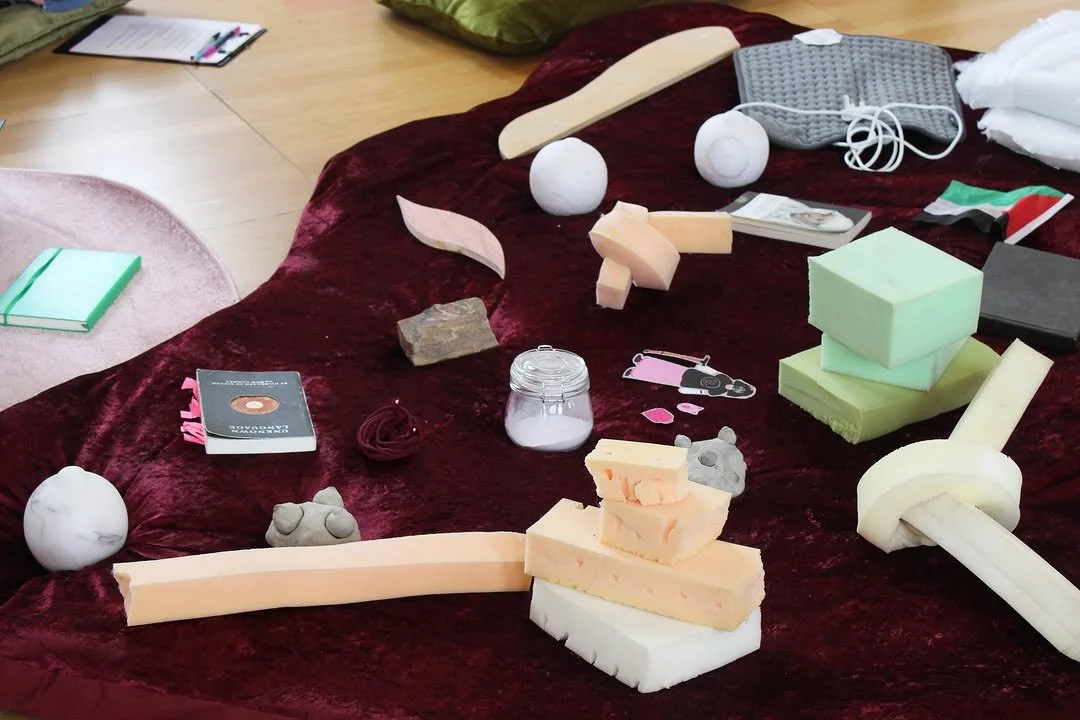 A collection of foam and clay objects on a red velvet surface, including foam blocks, rounded foam balls, clay shapes, a wooden rod, and other crafting materials.