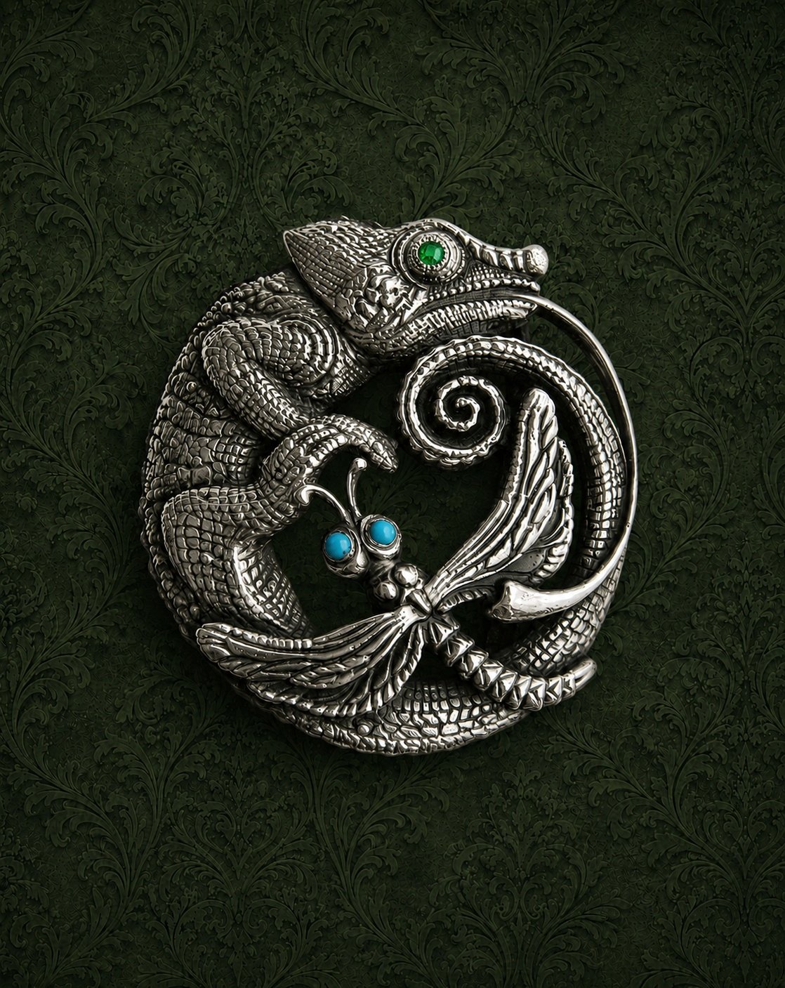 Silver dragon-shaped jewelry with green, blue, and clear gemstones on a dark green patterned background.