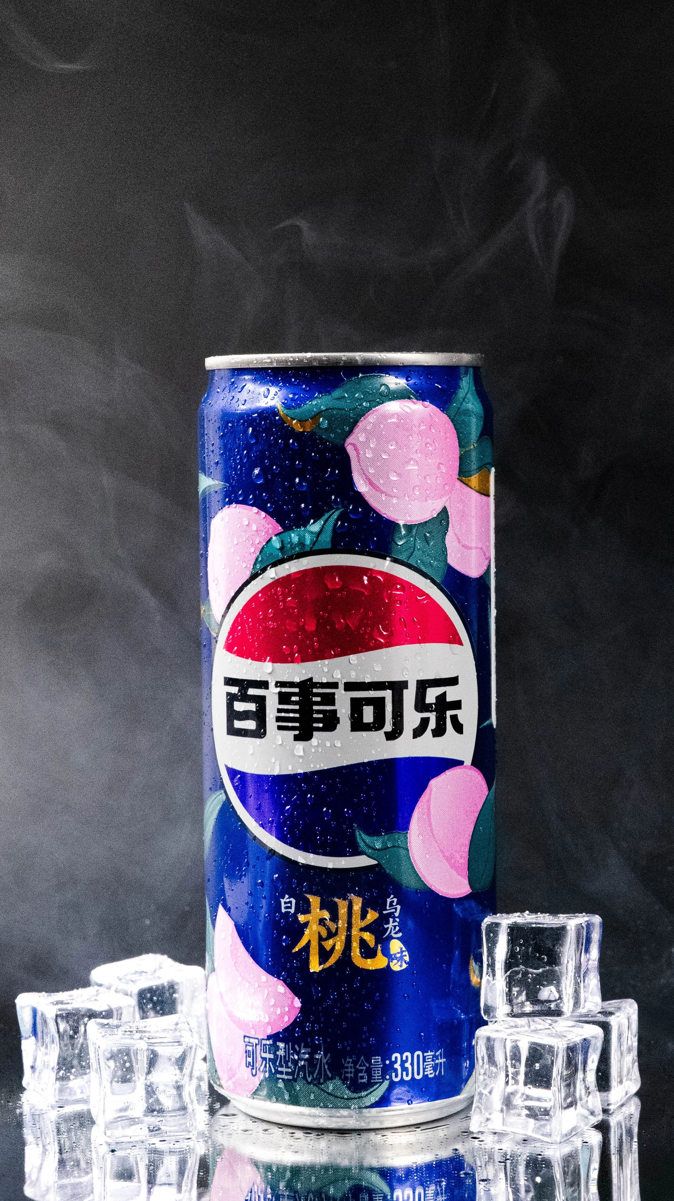 Une canette de soda bleu avec des motifs de pêches roses, des feuilles vertes et du texte en chinois, entourée de glaçons.