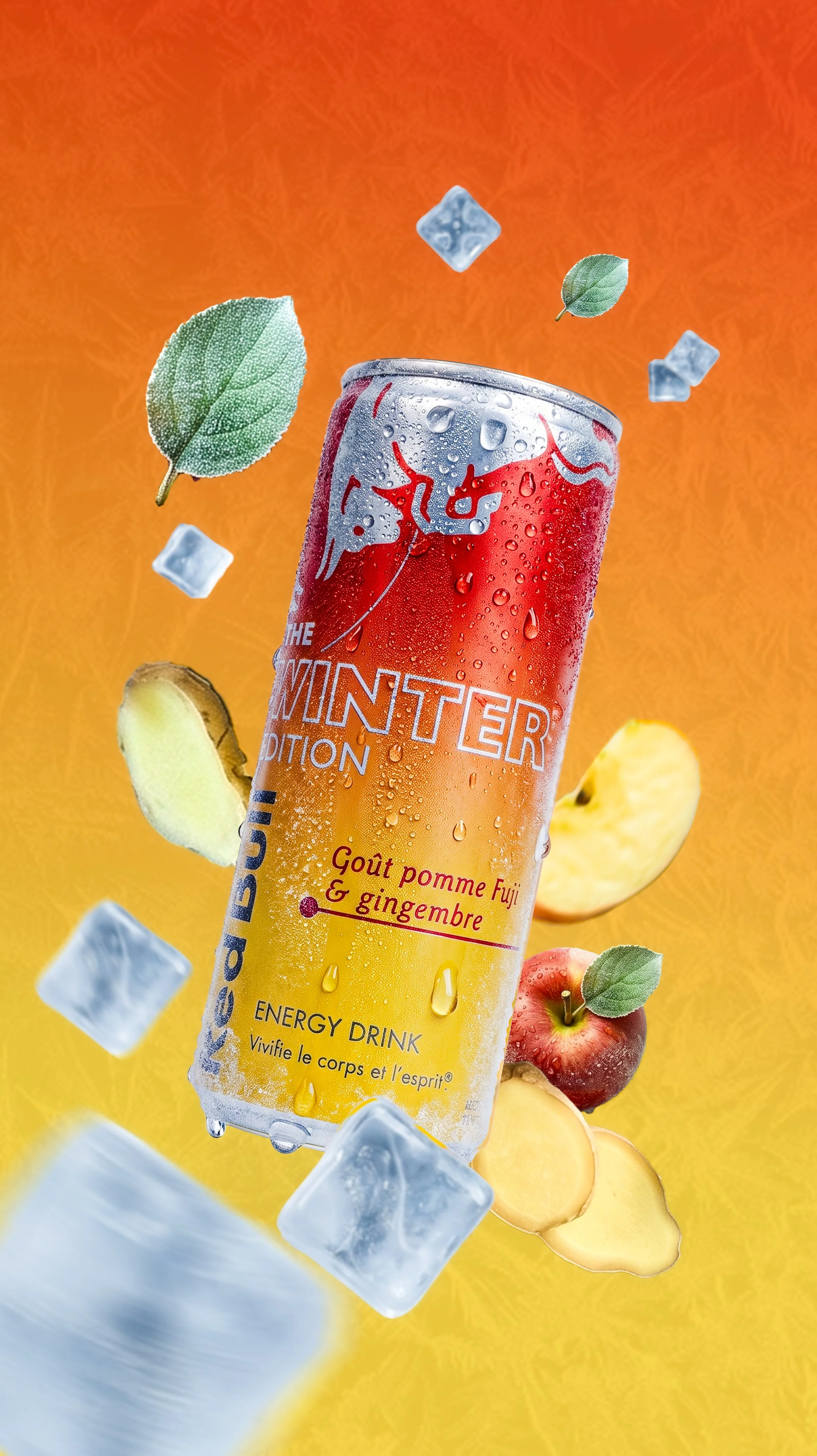 Une canette de boisson énergisante nommée 'The Winter Edition' avec un goût pomme Fuji & gingembre, entourée de glaçons, de feuilles de menthe, de pommes et de morceaux de gingembre, sur un fond dégradé orange et jaune.