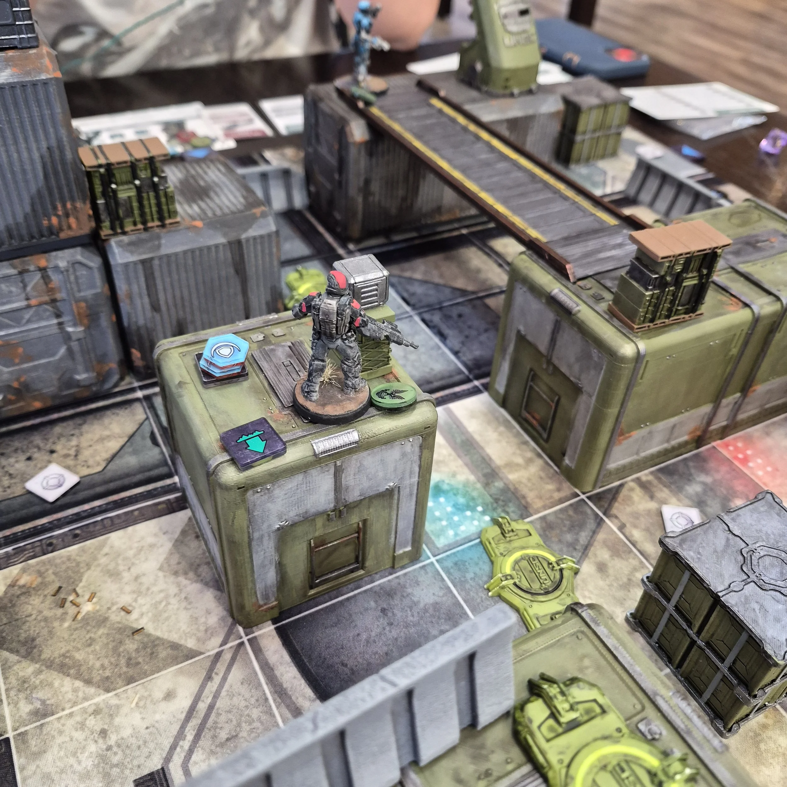A collection of miniature sci-fi city buildings and miniature figures on a gaming table.