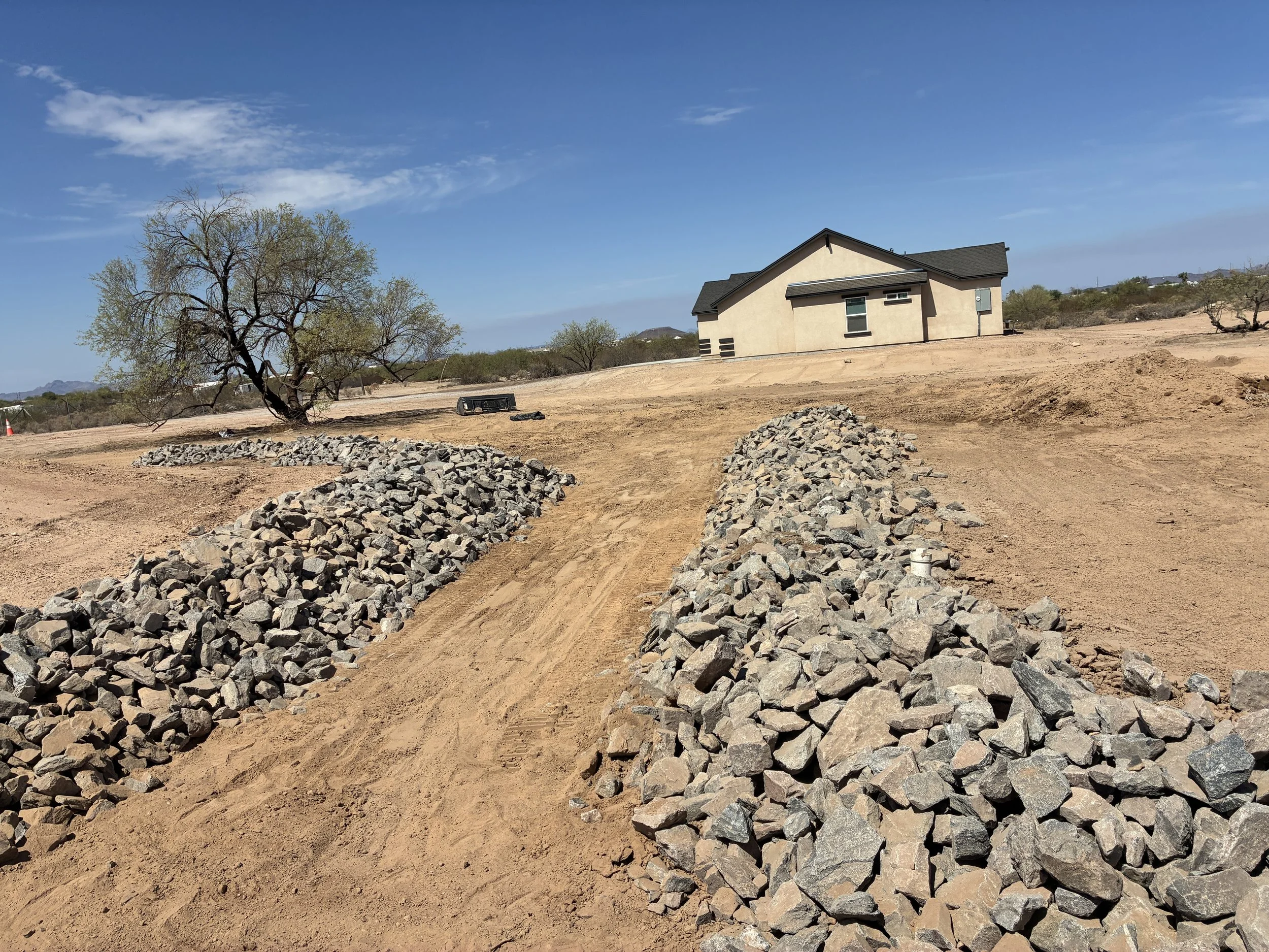 Rock-lined drainage swale directing stormwater away from an Arizona home