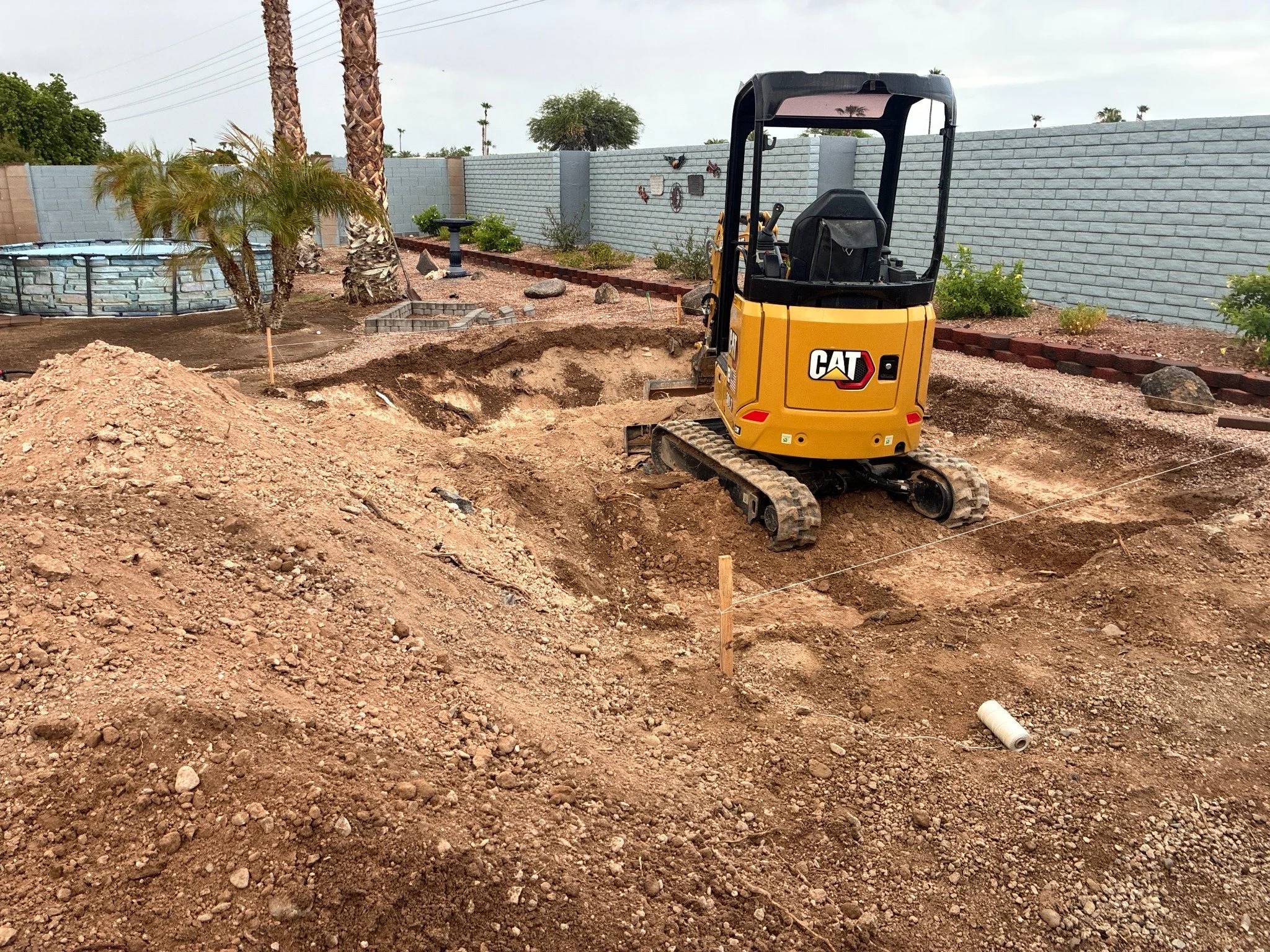 Compact excavator beginning a residential backyard pool excavation in Arizona