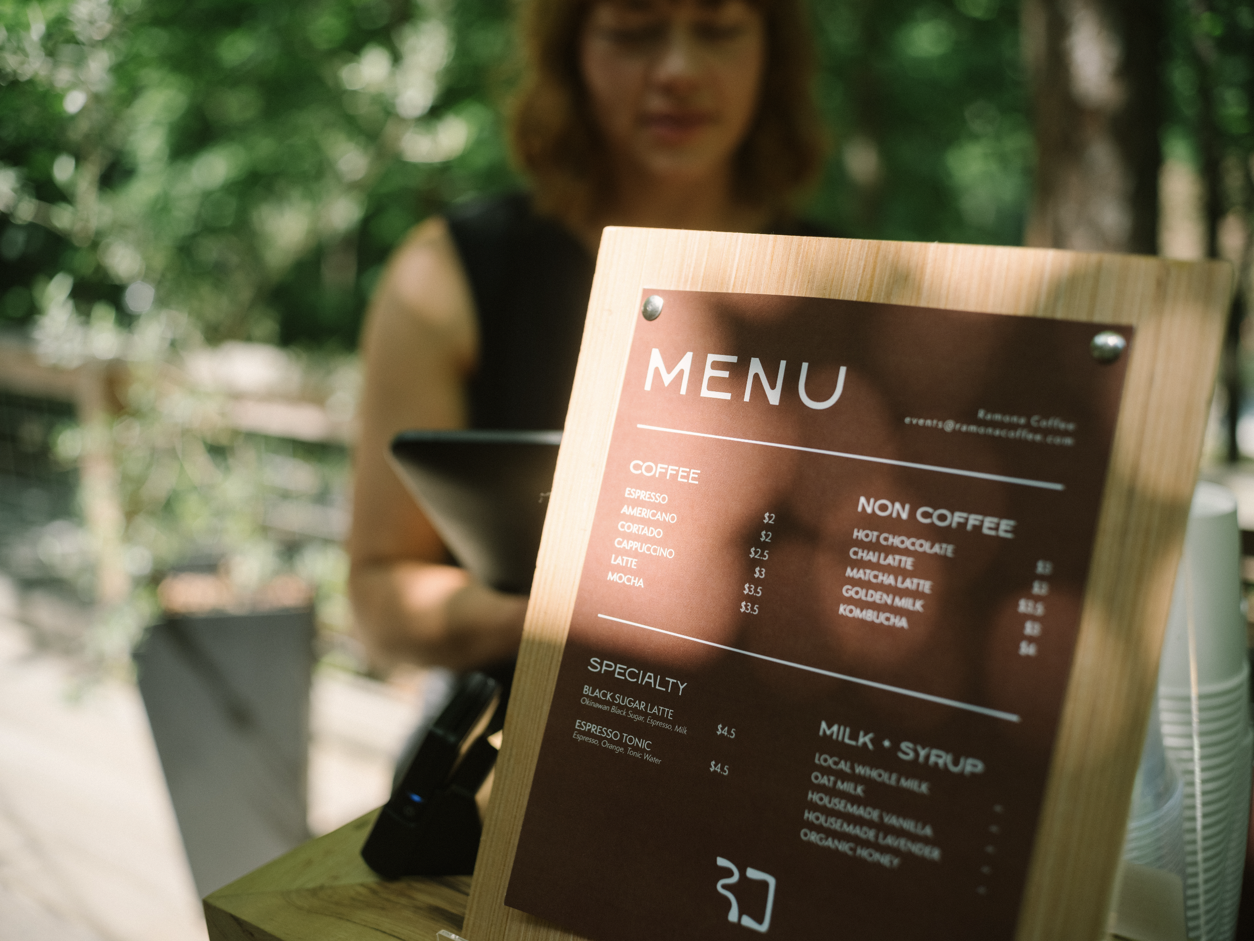 A person holding an outdoor menu for a premier custom espresso cart.