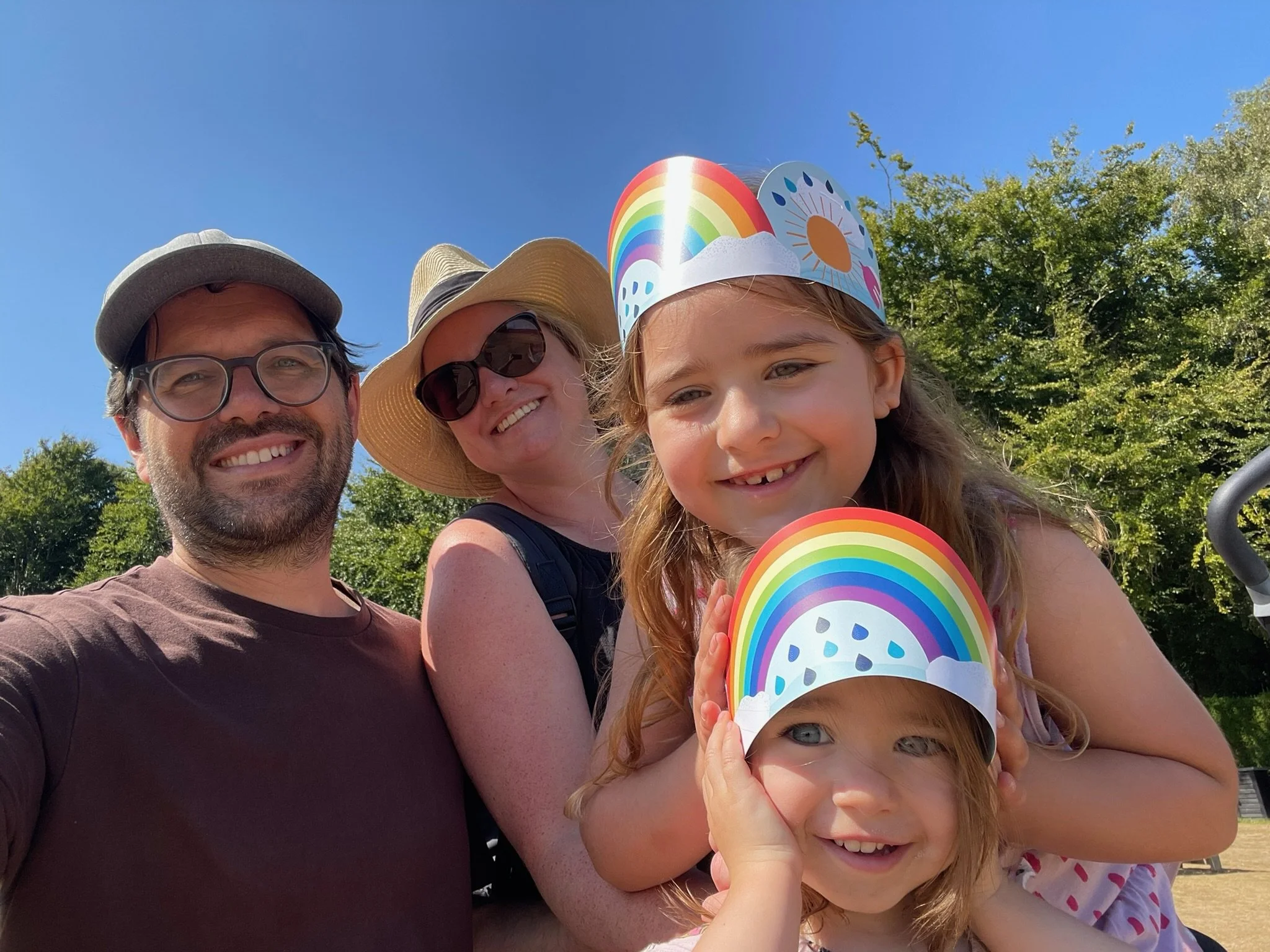 Image shows a man, woman and two children all smiling at the camera on a sunny day.
