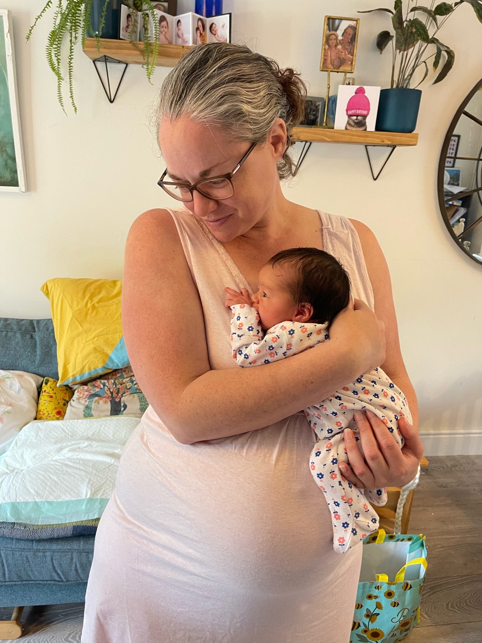 Woman at home standing whilst holding a newborn baby