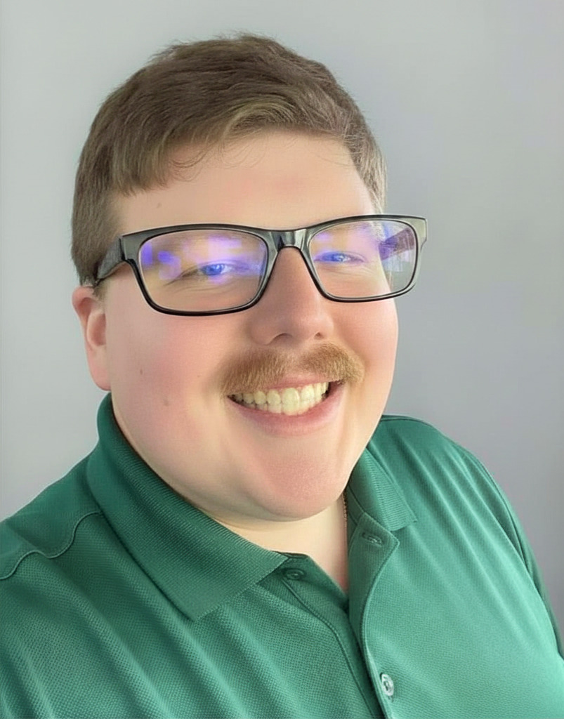 Craig Wolfley Jr. wearing glasses and a green polo shirt, posing for a selfie against a light background.