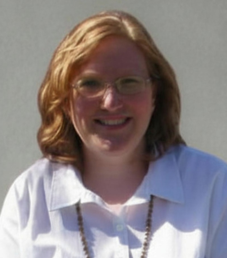 Christina Plumtree with shoulder-length red hair, glasses, and a white collared shirt smiling outdoors against a gray background.