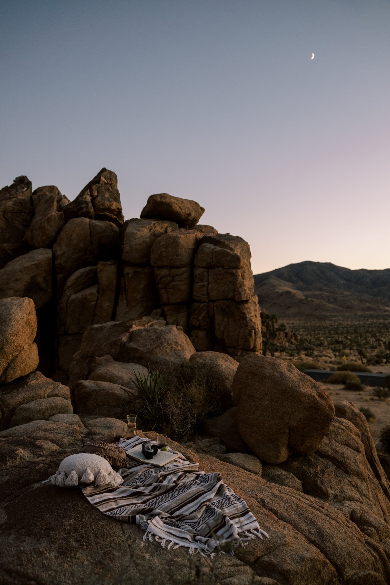 Pulled back shot of a bohemian picnic at sunset/dusk in the dreamy desert