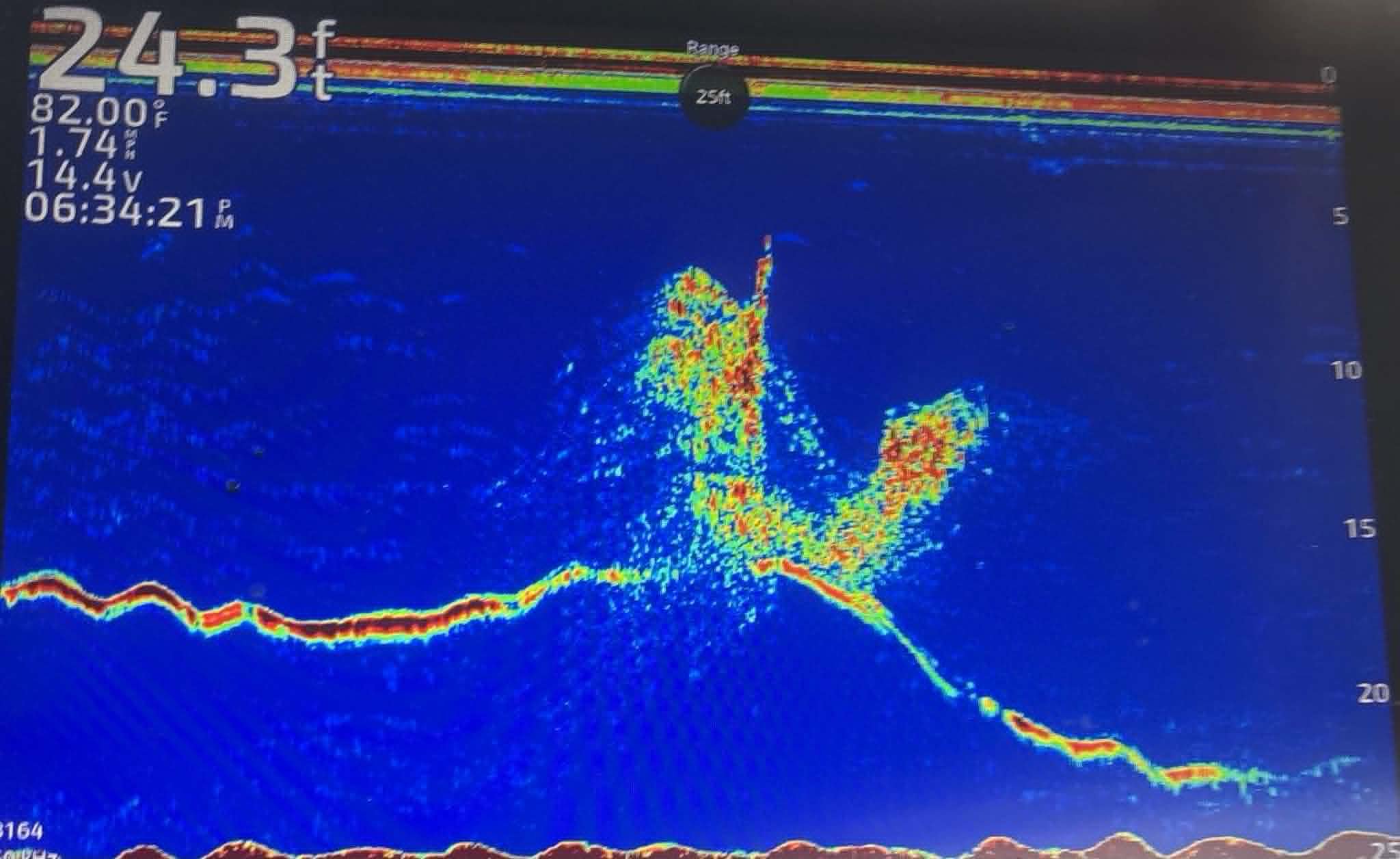 A fishfinder screen displaying a sonar image of underwater terrain, fish, and water depth, with colorful data lines and measurements.
