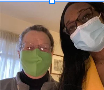 Two people wearing face masks taking a selfie indoors.