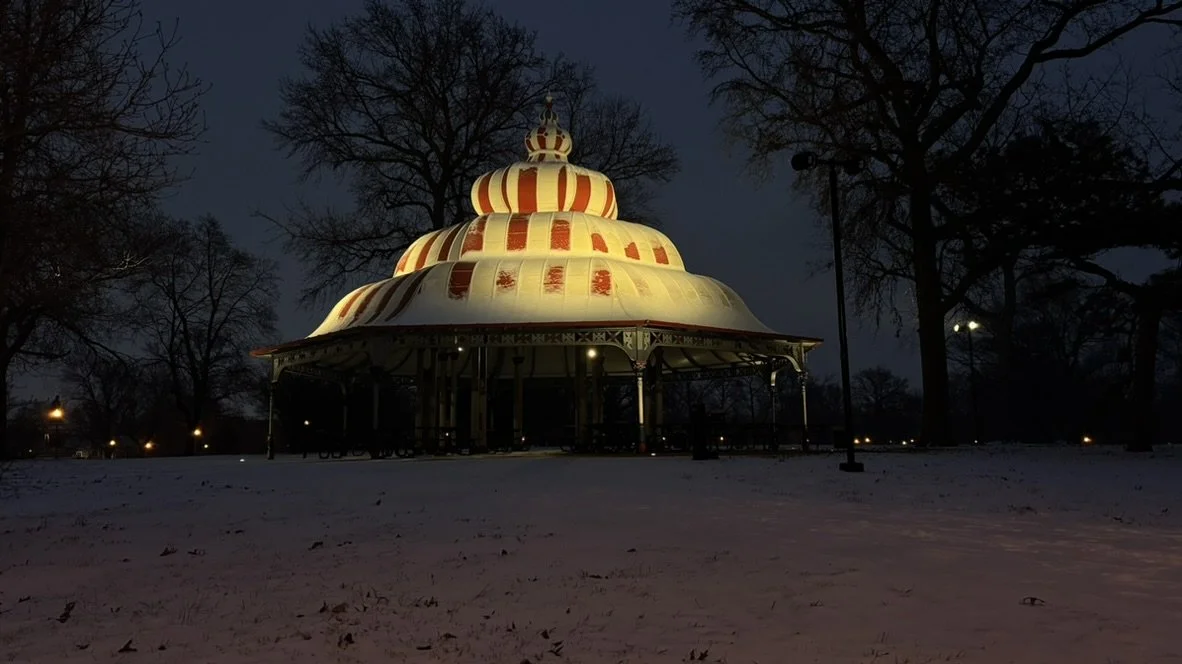 Photo depicts the Turkish Pavilion in Tower Grove Park, a large structure with red and white horizontal stripes. The roof is covered in a thin sheet of snow.