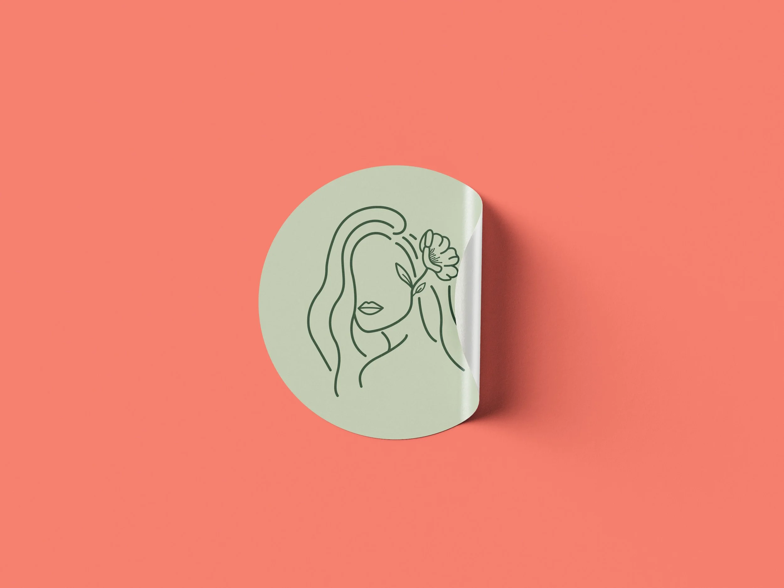 Flowerful Hair Salon brand identity round sticker mockup featuring a sage green circular sticker with a dark green fine-line illustration of a woman with long flowing hair holding a flower, peeling at the corner, on a coral pink background.