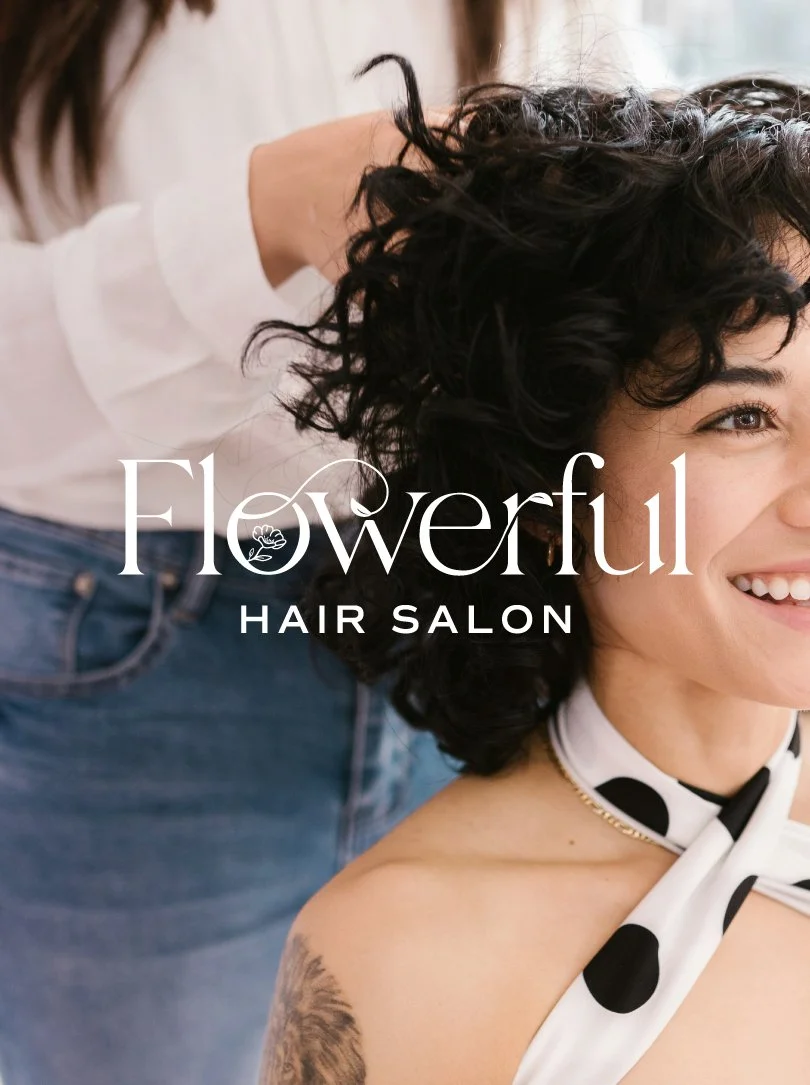 Yasmine Design Co. – Flowerful Hair Salon logo application mockup featuring an elegant floral wordmark overlaid on a photo of a smiling woman with curly hair being styled.