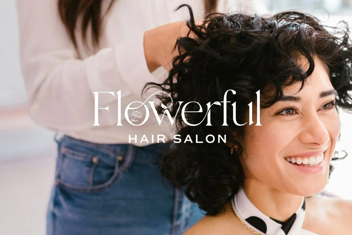 Flowerful Hair Salon brand identity logo application mockup showing the white serif wordmark overlaid on a lifestyle photo of a smiling woman with short curly dark hair getting her hair styled by a hairstylist.