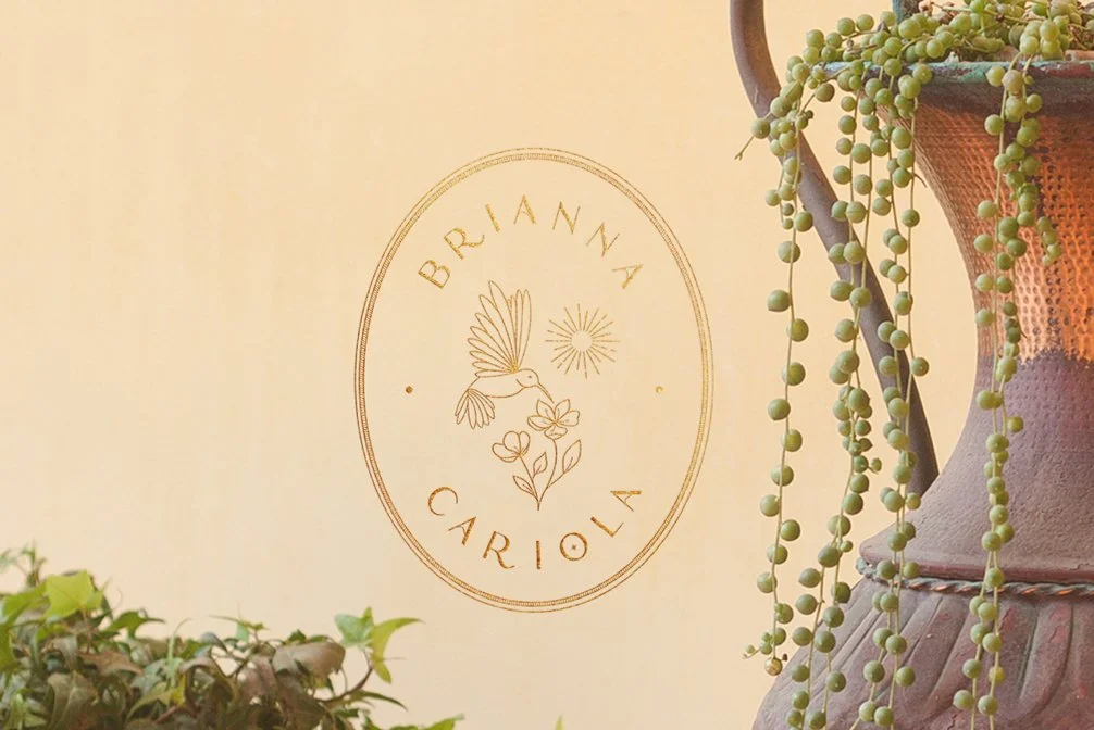 Yasmine Design Co. – Brianna Cariola brand identity design featuring an elegant gold oval logo mockup with a hummingbird, sun, and floral illustration on a warm neutral background.