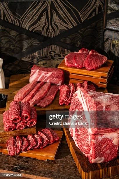 Assorted cuts of raw beef on wooden boards for grilling or cooking.