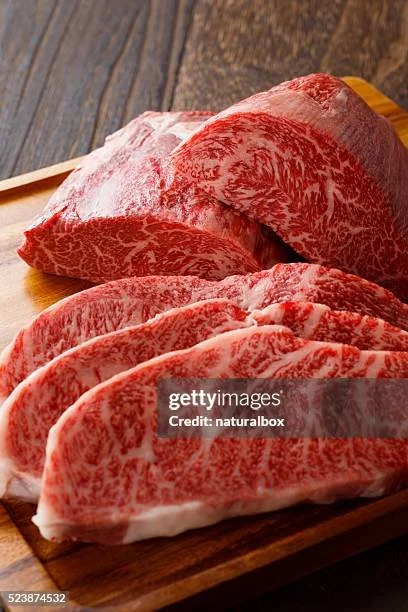 Slices of marbled beef on a wooden cutting board.