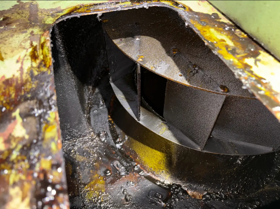 Close-up of a worn and greasy mechanical part with yellow and black paint, showing grease buildup.
