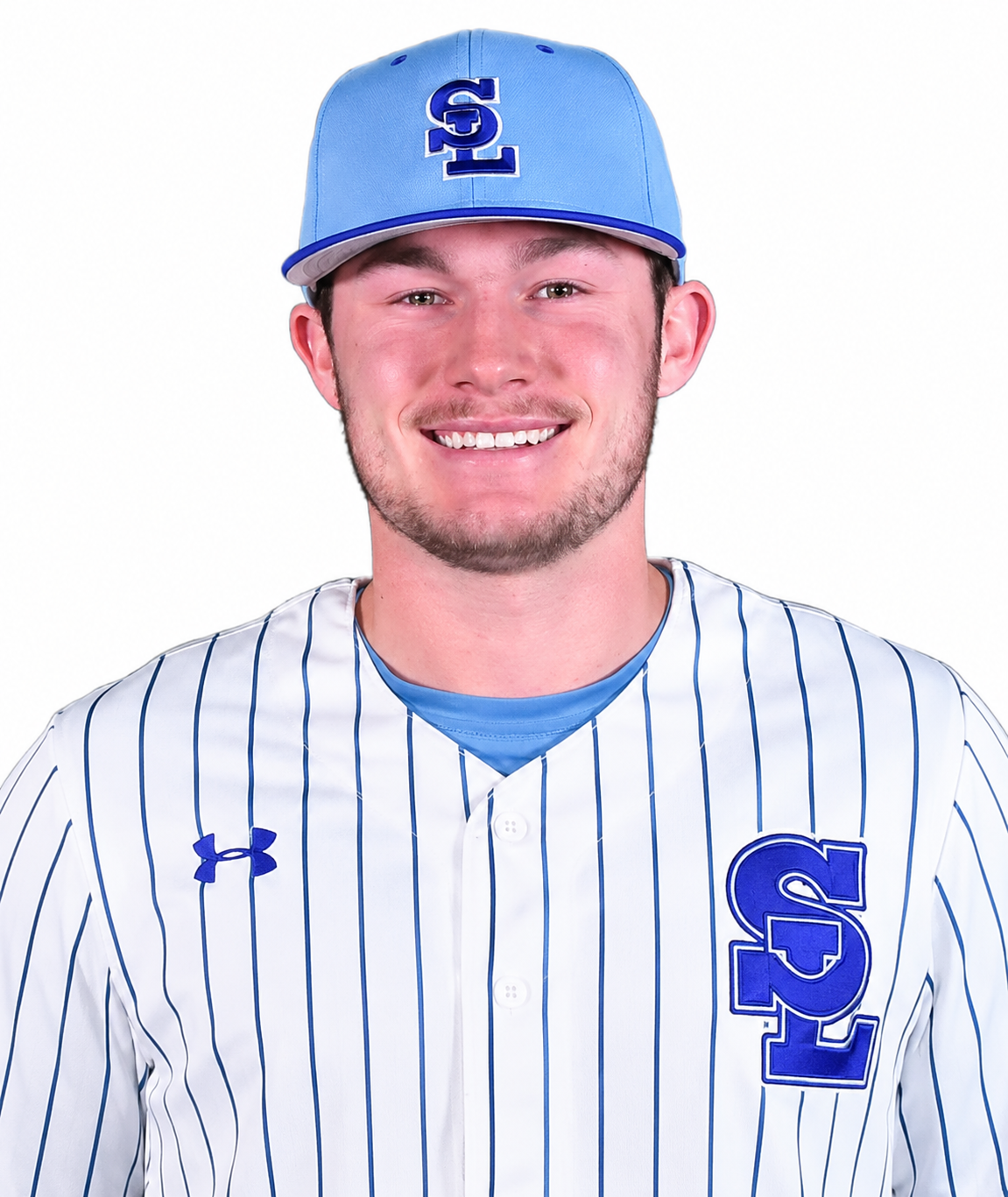 A young man in a baseball uniform, wearing a blue cap upside down and smiling, against a white background.