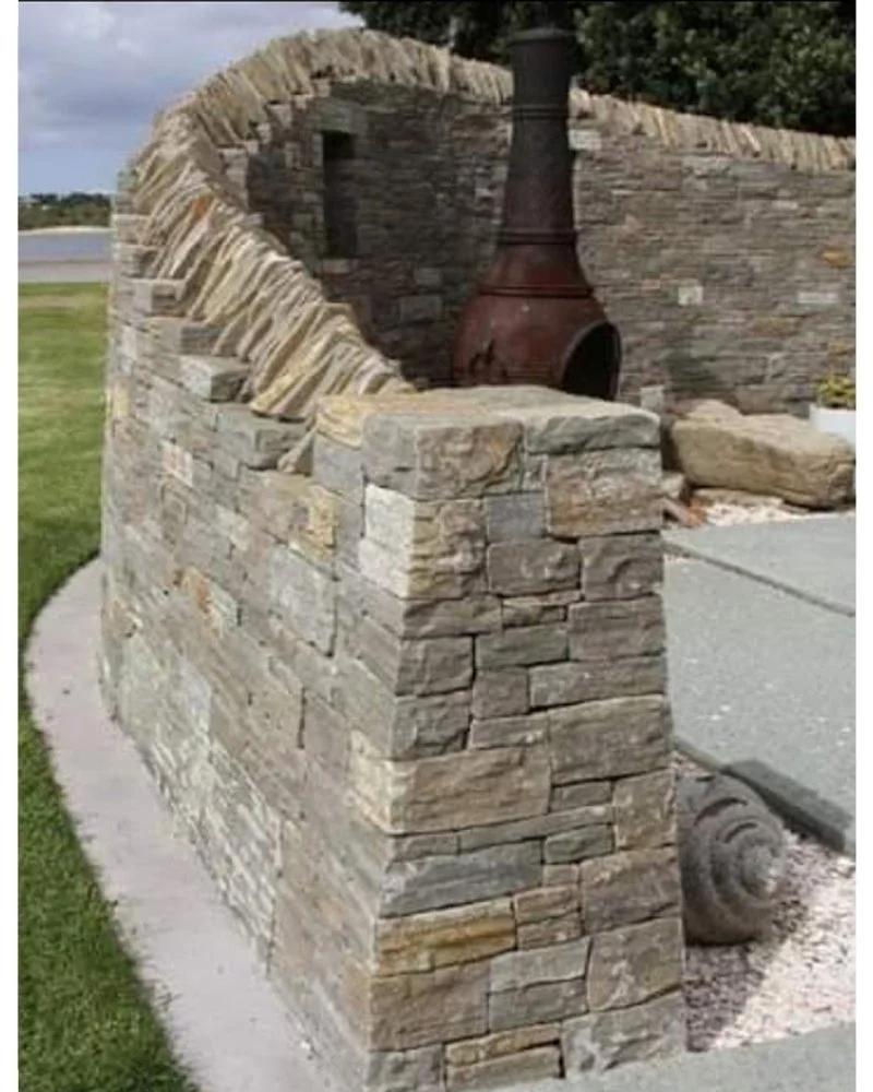 Outdoor stone fireplace with chimney, built with stacked flat stones.