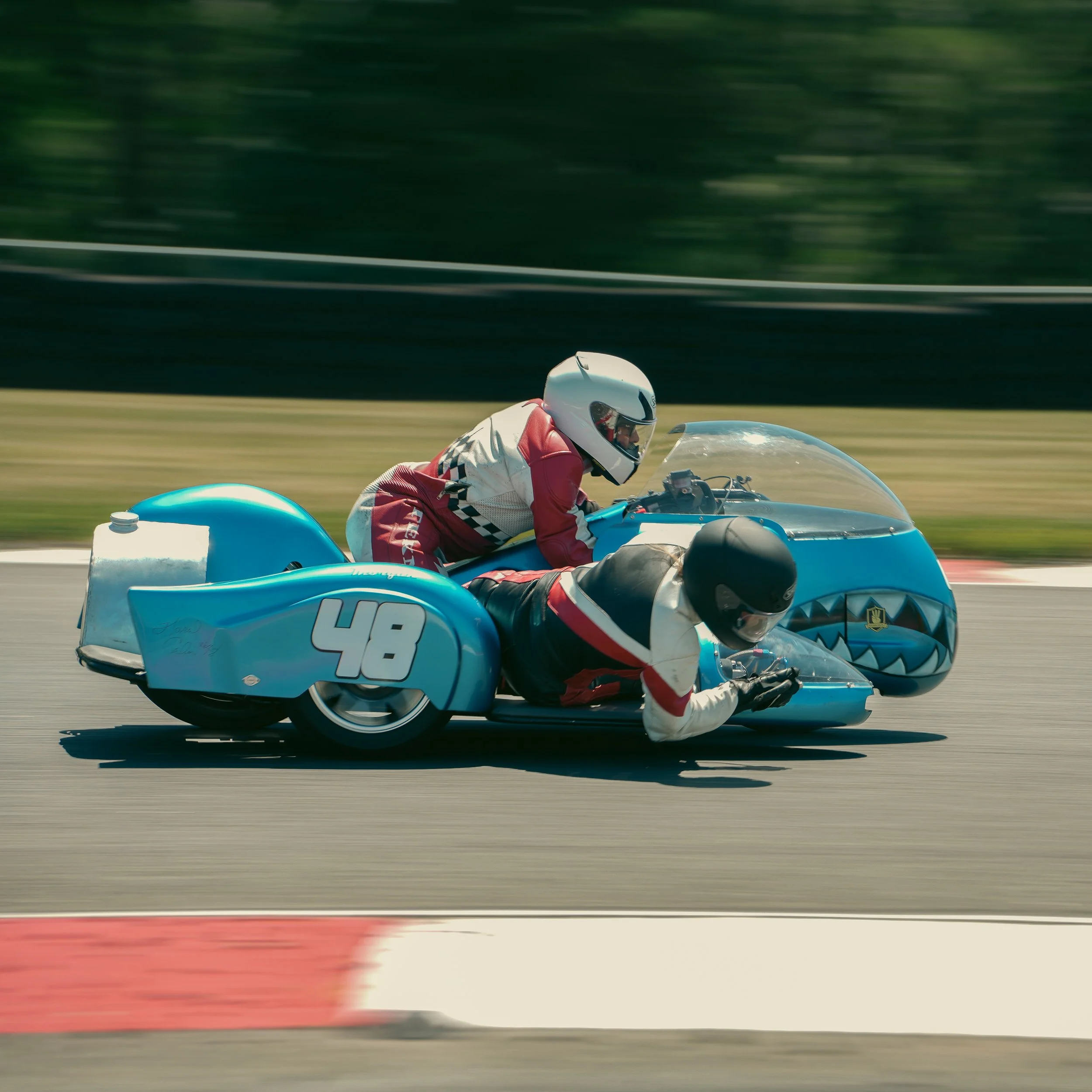 A motorcycle racer in a red and white suit and white helmet riding a blue racing motorcycle on a race track.