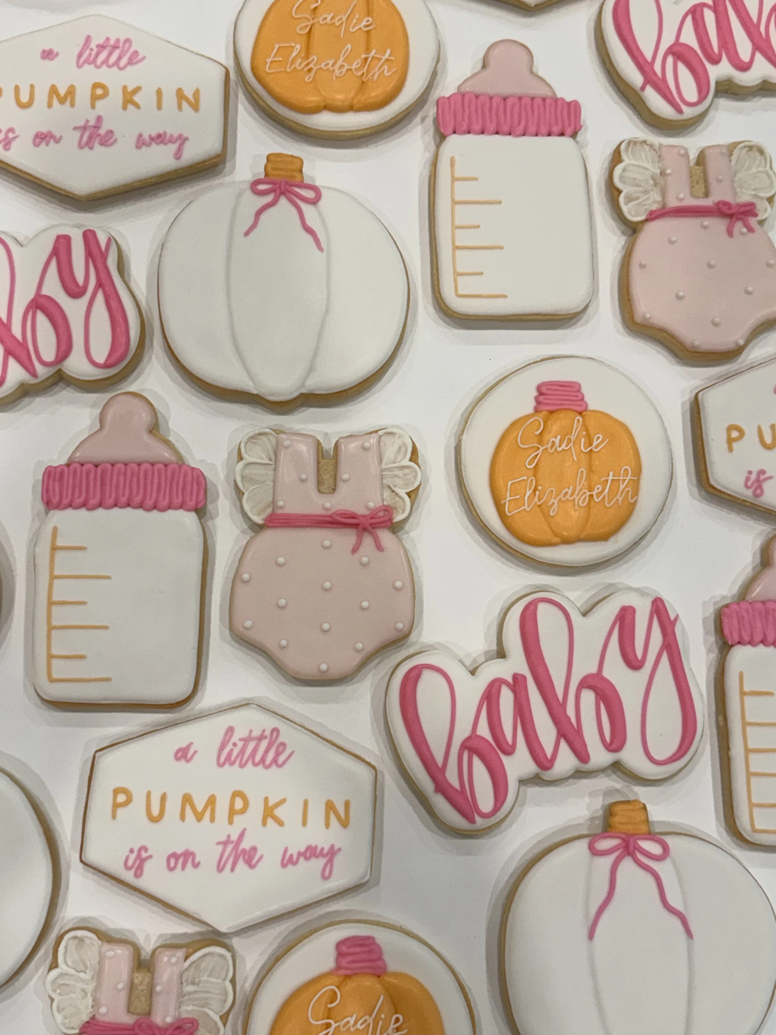 Collection of decorated cookies with autumn and baby-themed designs and messages.