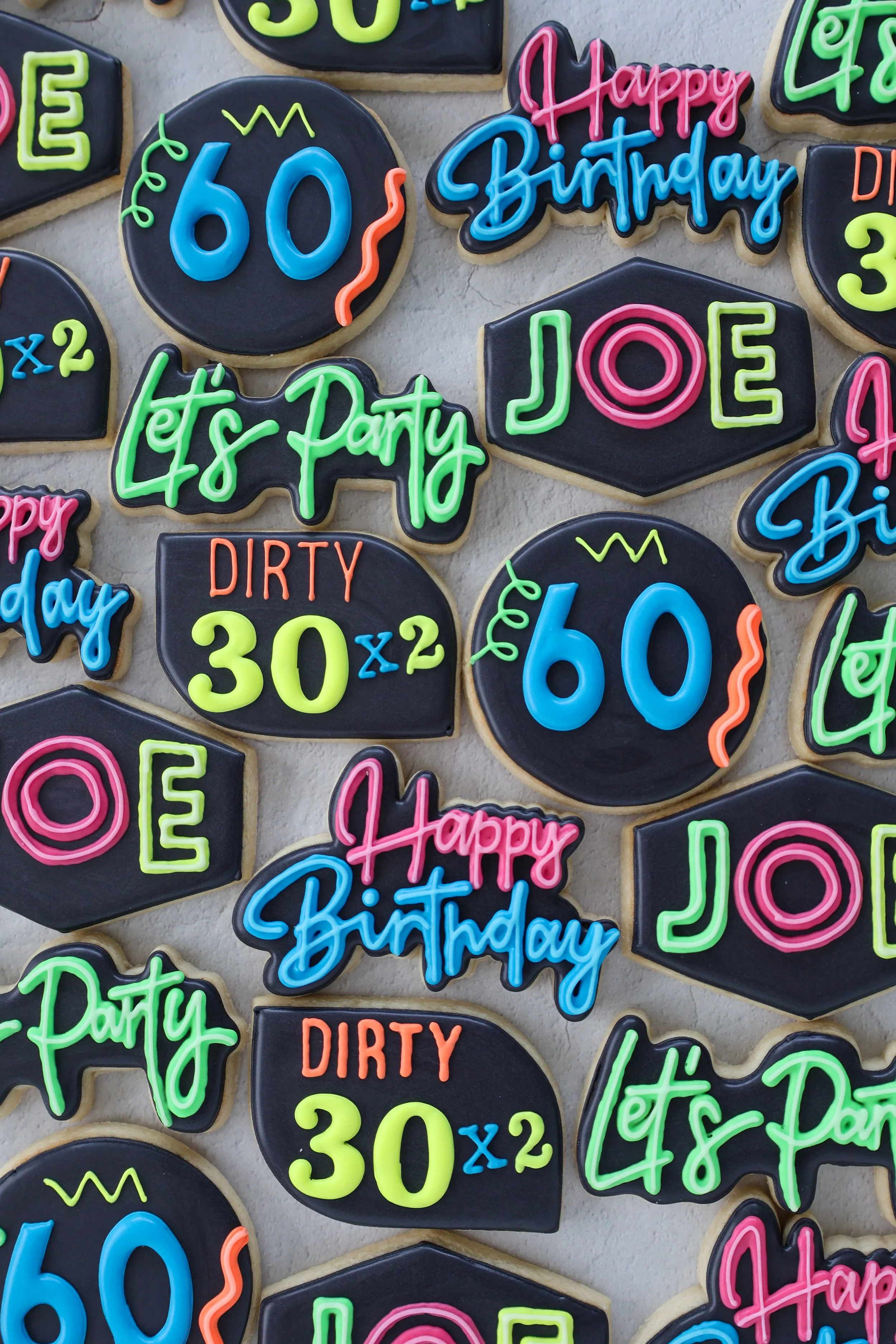 Colorful birthday cookies with neon-colored icing and messages including 'Happy Birthday', 'Let's Party', and '60' in various shapes and designs.