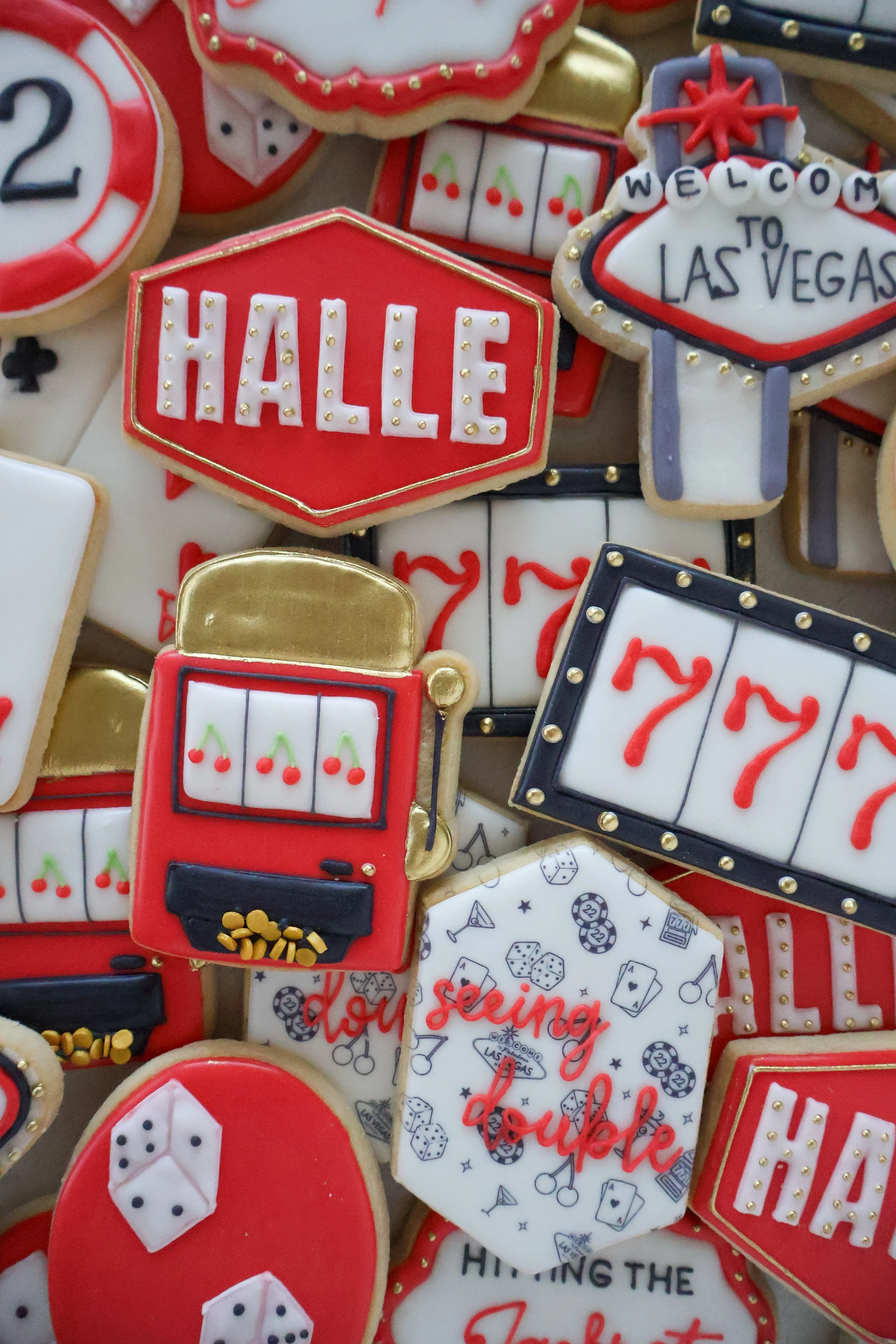 Cookies decorated with casino and Las Vegas themes, including dice, playing cards, slot machines, and signs reading 'HELLO,' 'WELCOME TO LAS VEGAS,' and other messages.