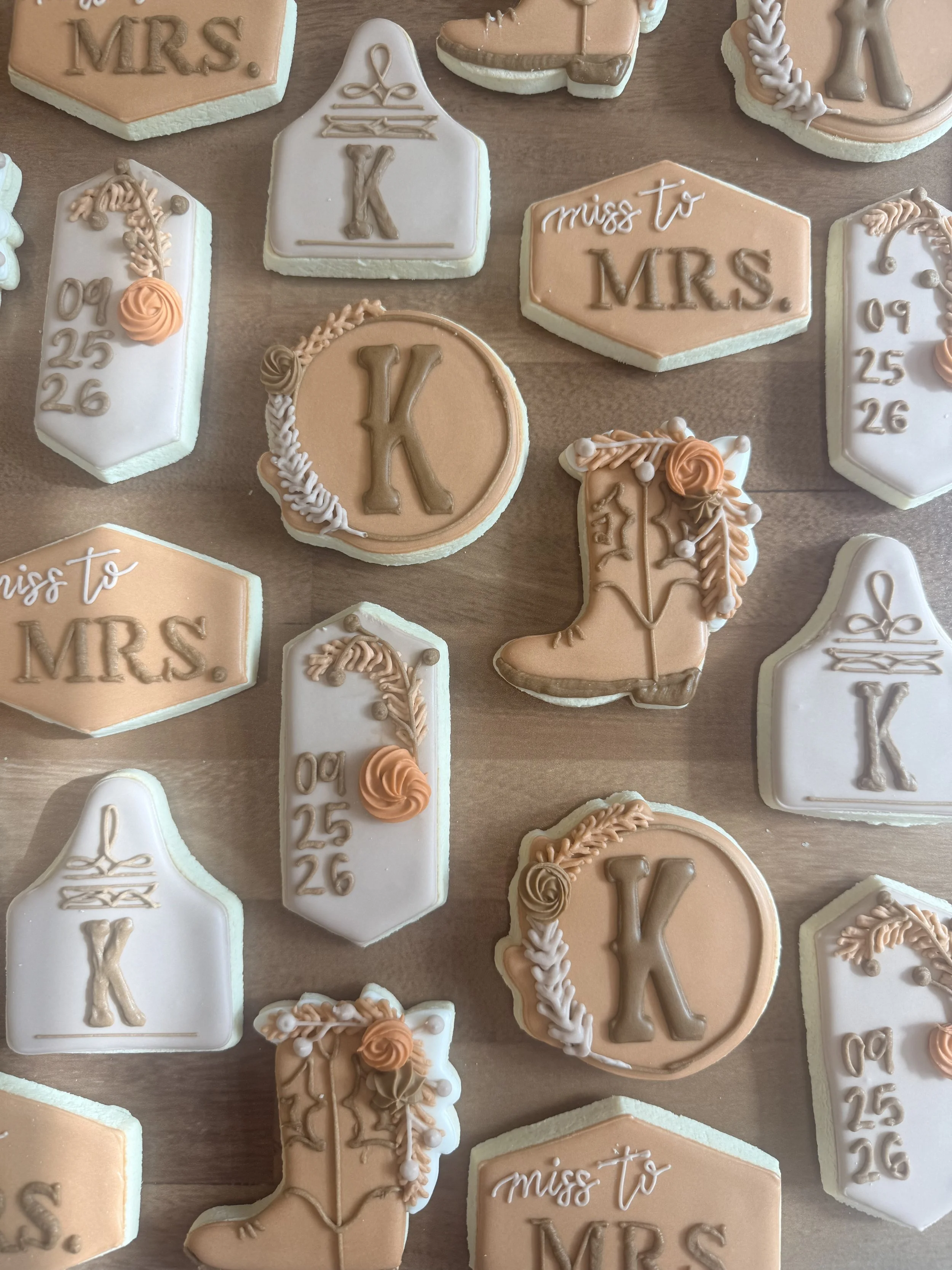 A variety of decorated cookies with pastel colors, some shaped like keys, locks, and tags, with words like "miss to MRS" written on them for a wedding or bridal shower celebration.