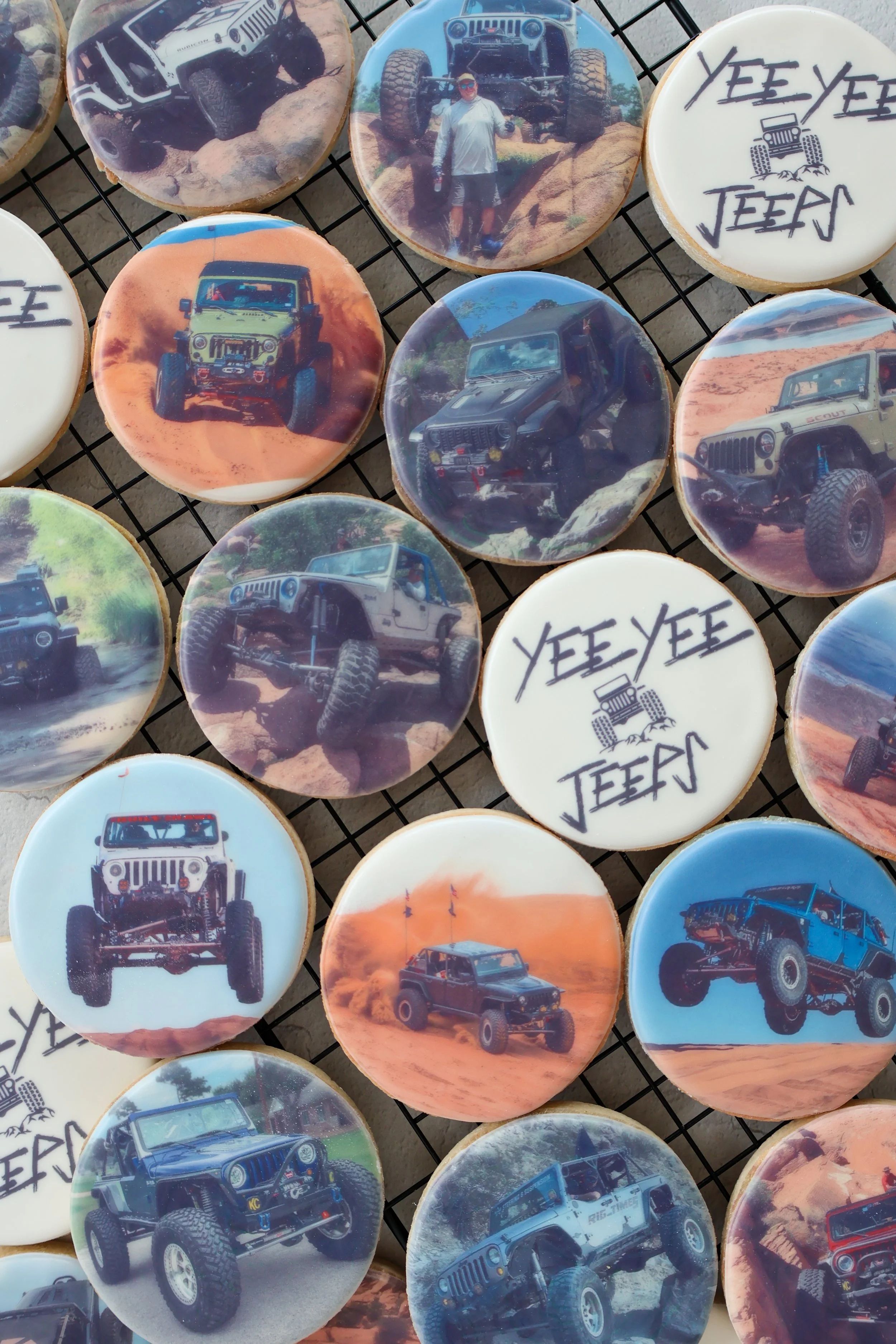 Cookies decorated with images of various Jeep vehicles, desert landscapes, and a person standing next to a Jeep