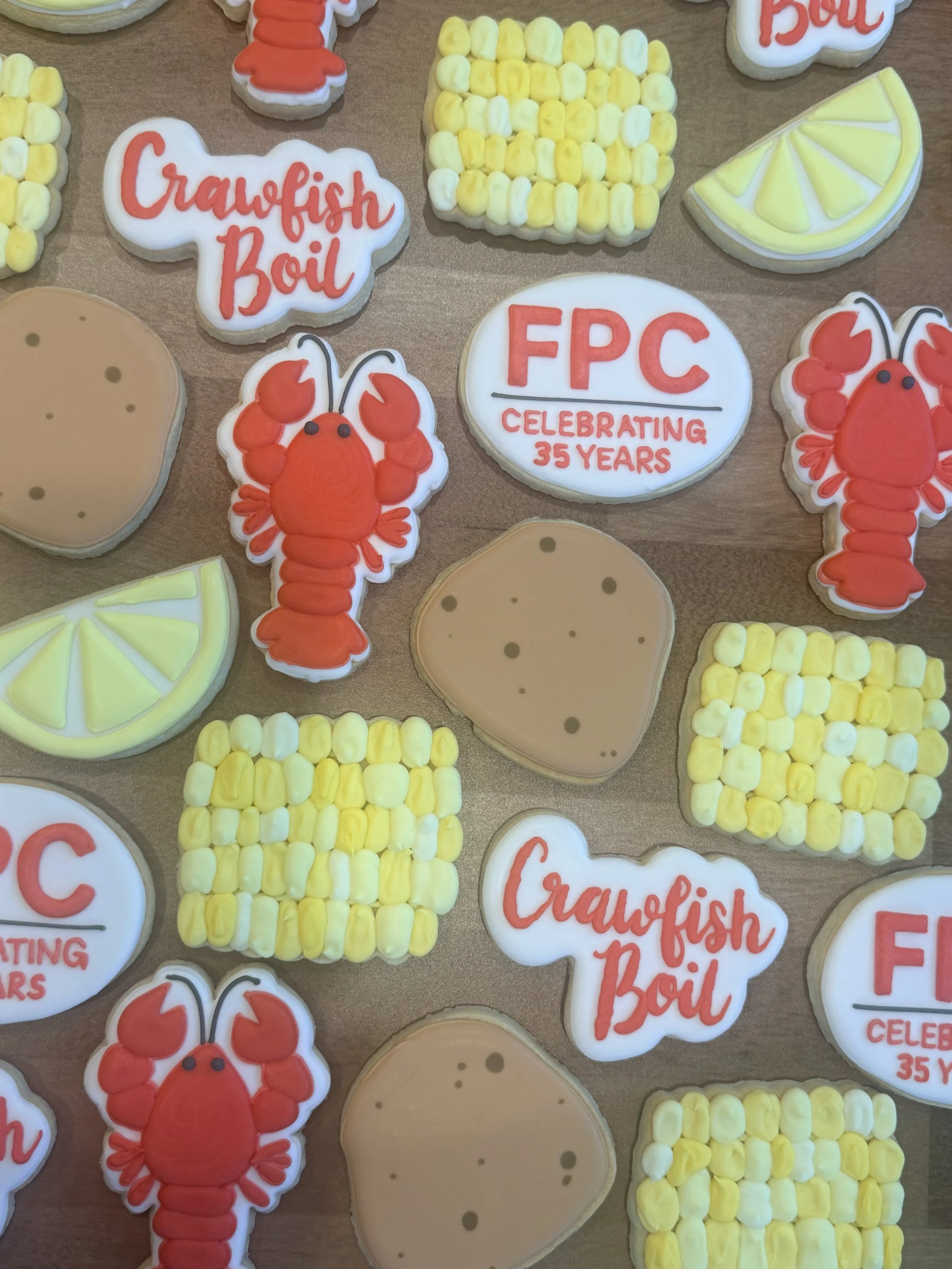 Decorative cookies celebrating a company’s 35th anniversary, including cookies shaped like lobsters, lemon slices, and circular cookies with text such as 'Crayfish n' Boil' and 'FPC Celebrating 35 Years'.
