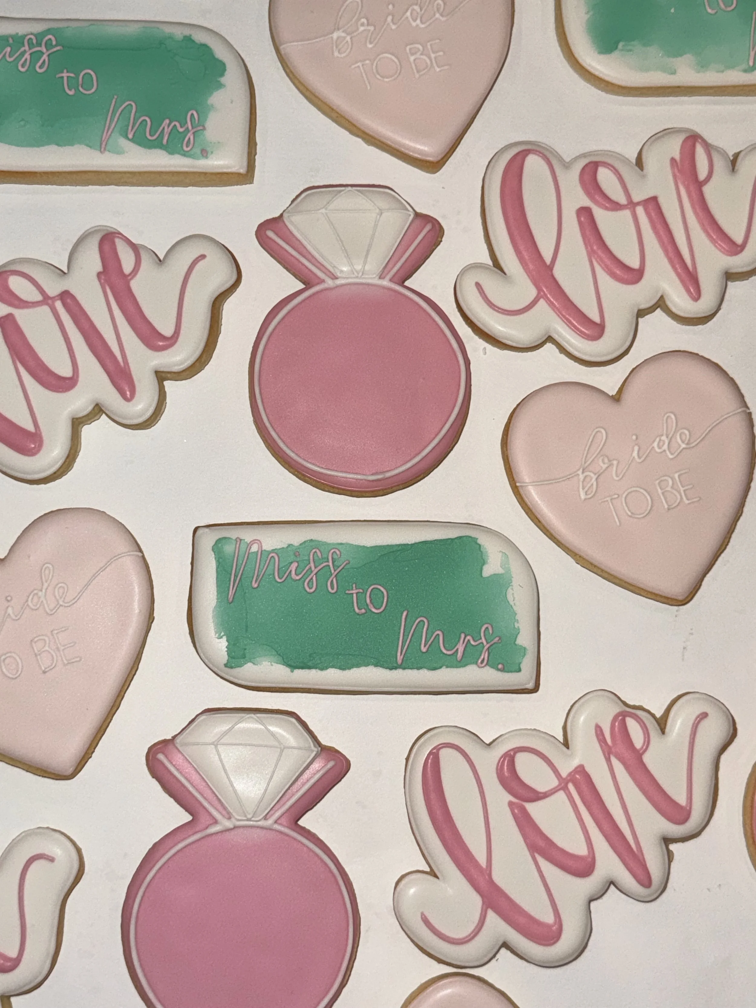 Various decorated cookies with messages like 'Miss to Mrs.', 'bride to be', and 'love' in pink and green pastel colors.