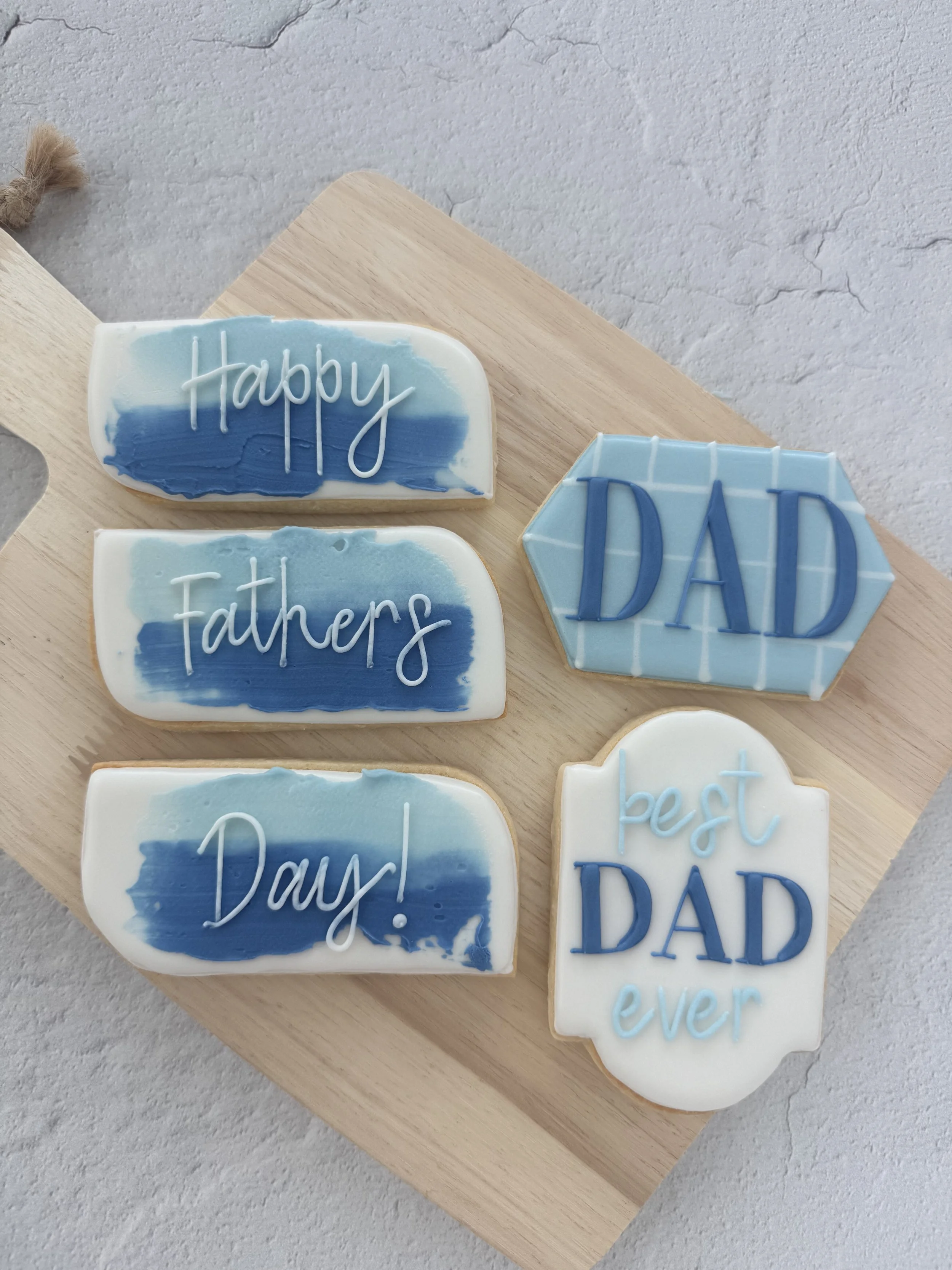 Decorative cookies with messages for Father's Day, featuring blue and white color schemes and speech bubble shapes.