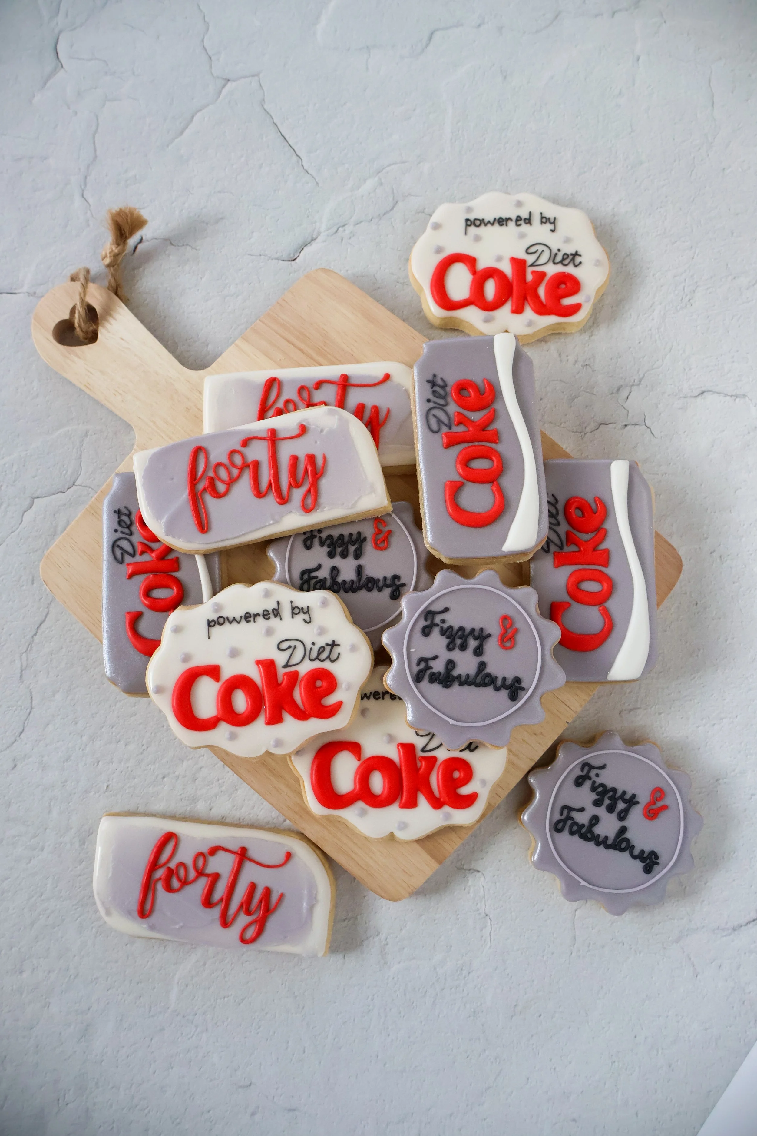Decorative cookies on a wooden cutting board with text such as "forty," "diet Coke," and "Fizzy & Fabulous."